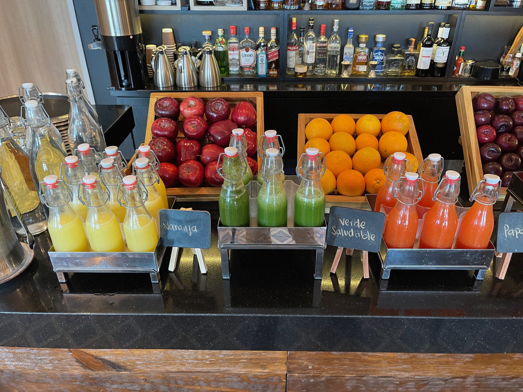 a group of bottles of juice and fruit on a counter