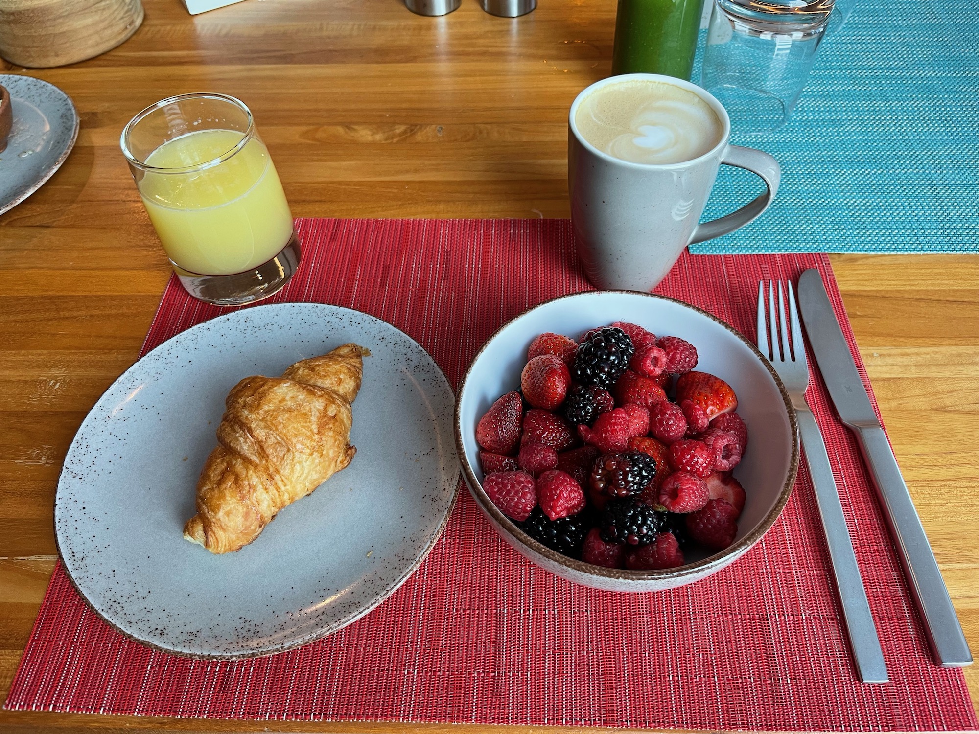 a plate of fruit and a croissant on a table