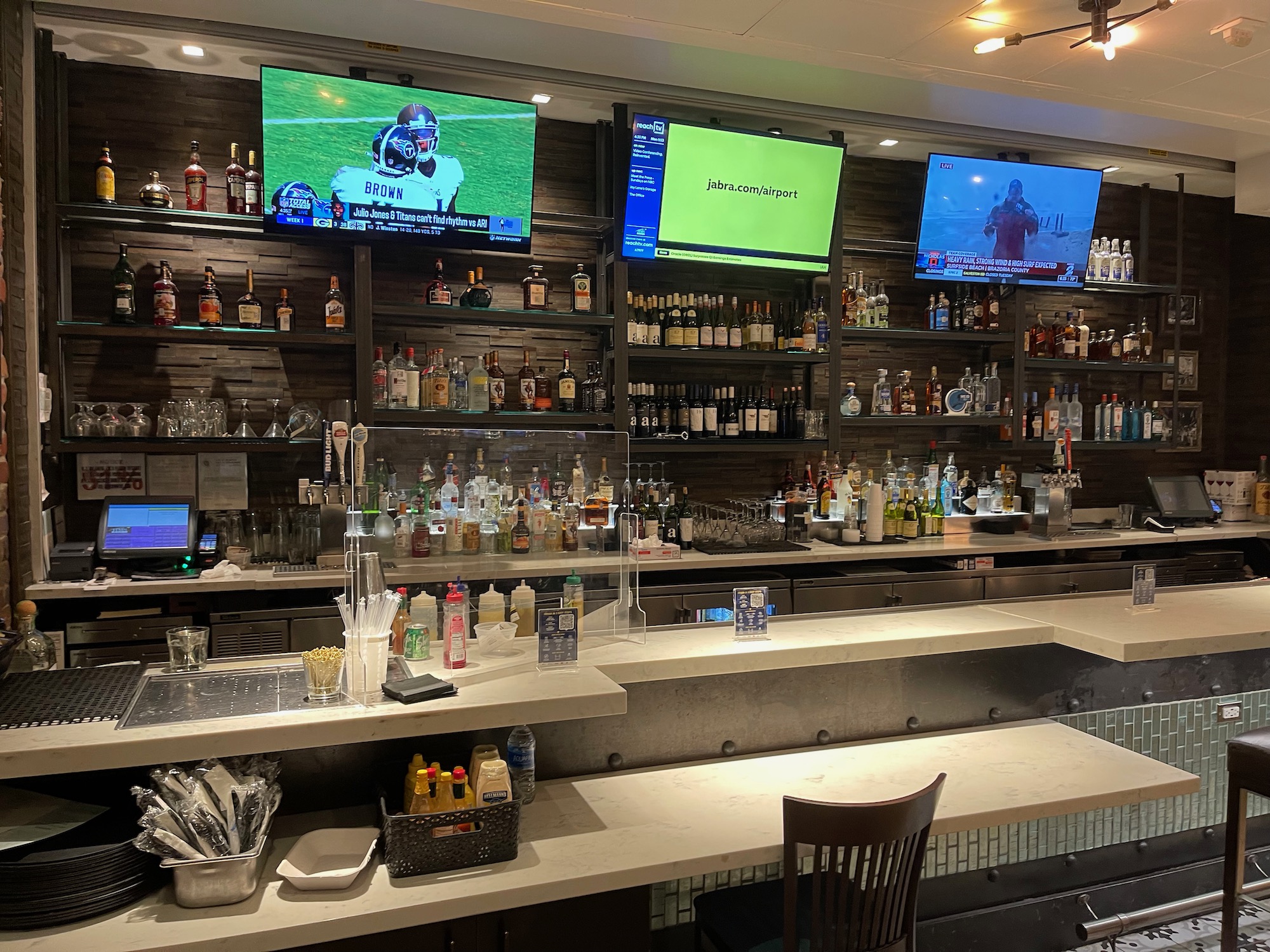 a bar with a television and bottles on the wall