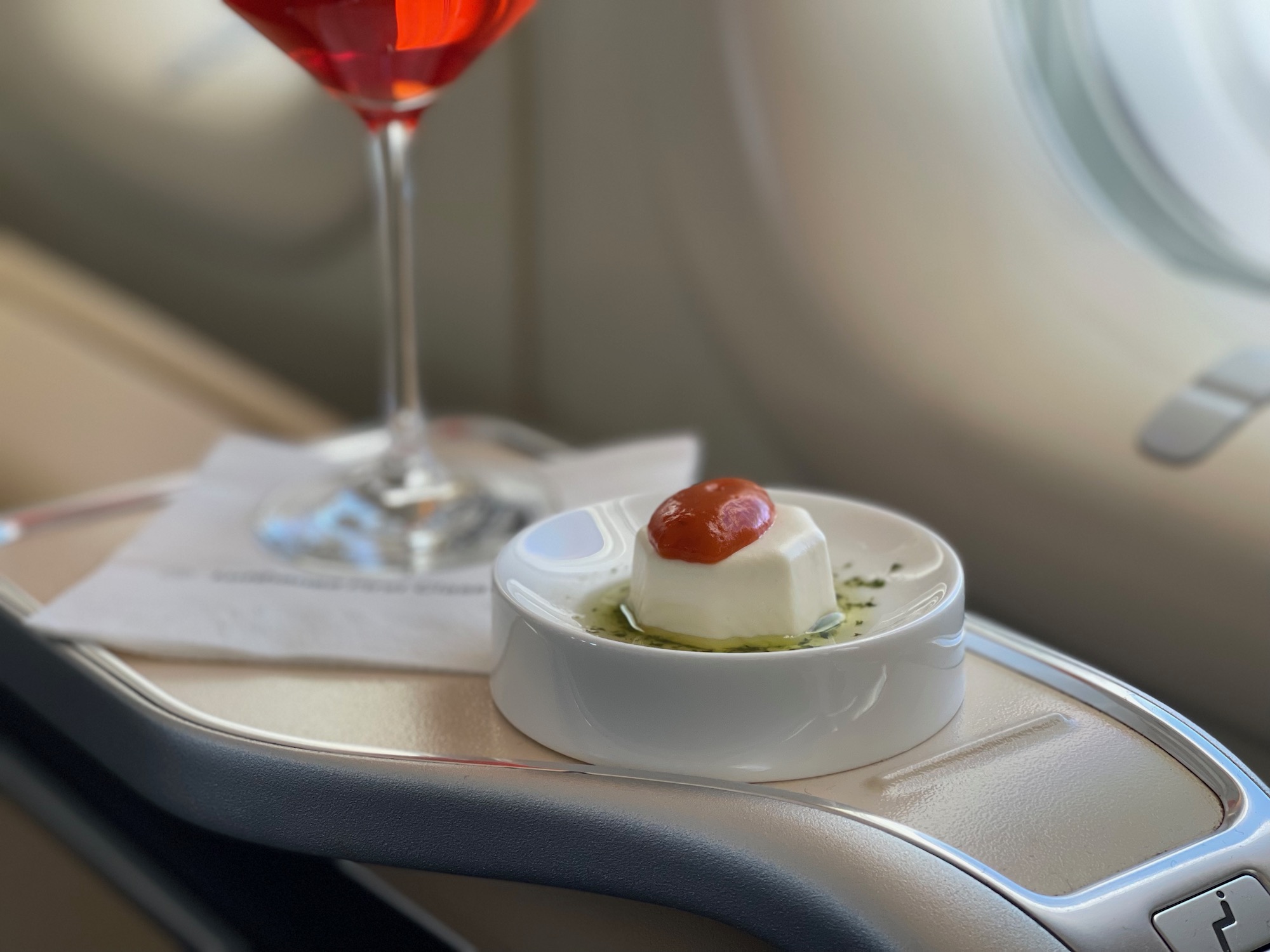 a small dish with food on it next to a glass of red liquid