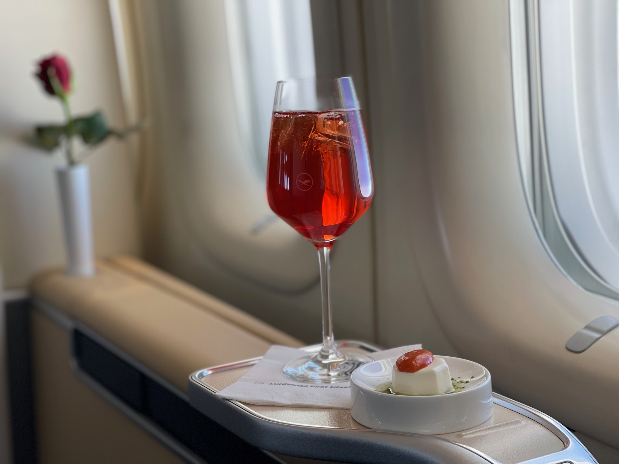 a glass of red liquid next to a small dish of cheese