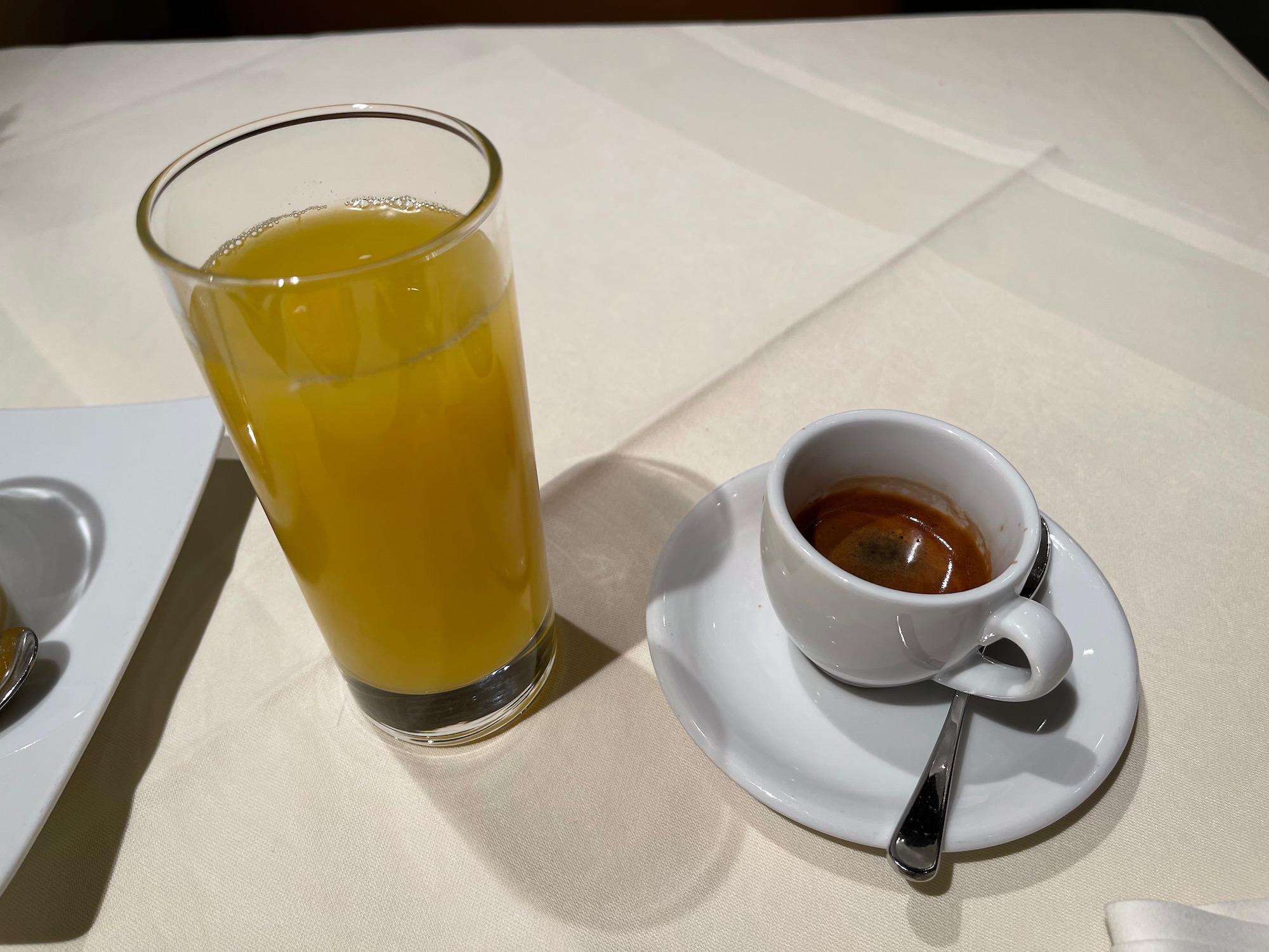 a cup of coffee and a glass of orange juice on a white table