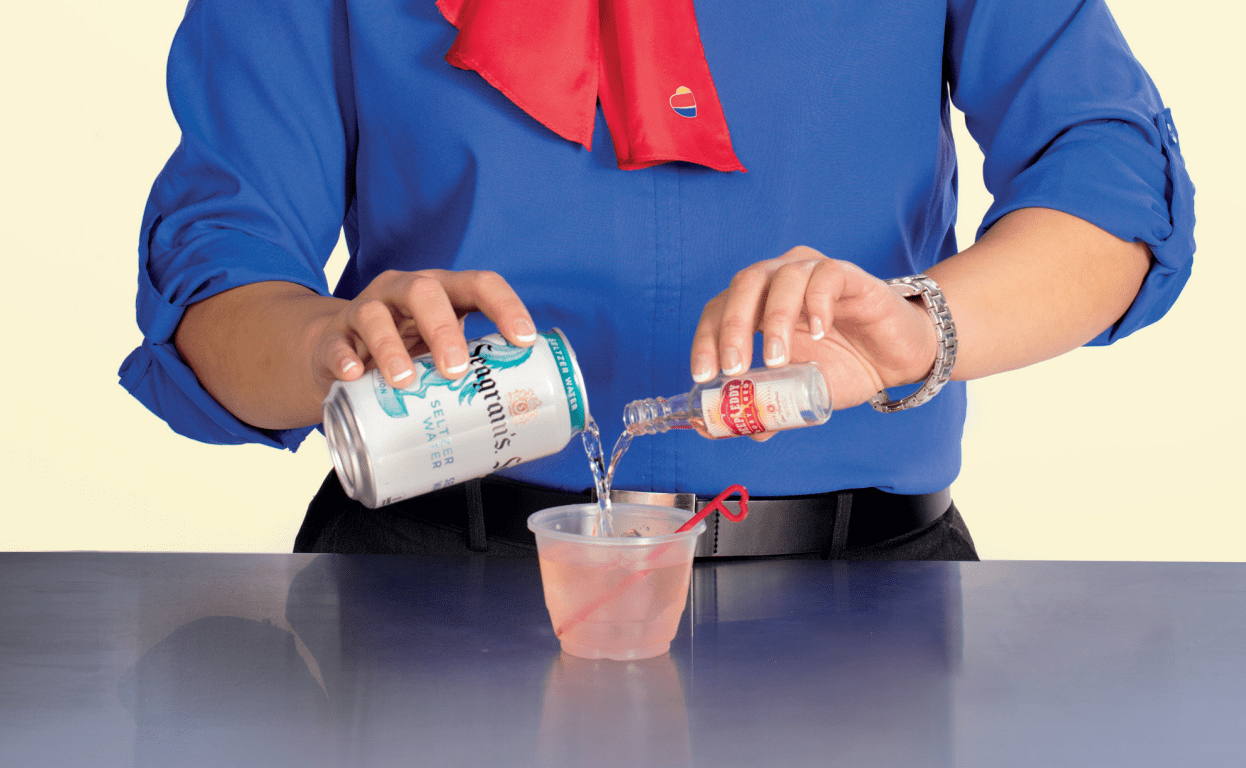 a person pouring a drink into a cup