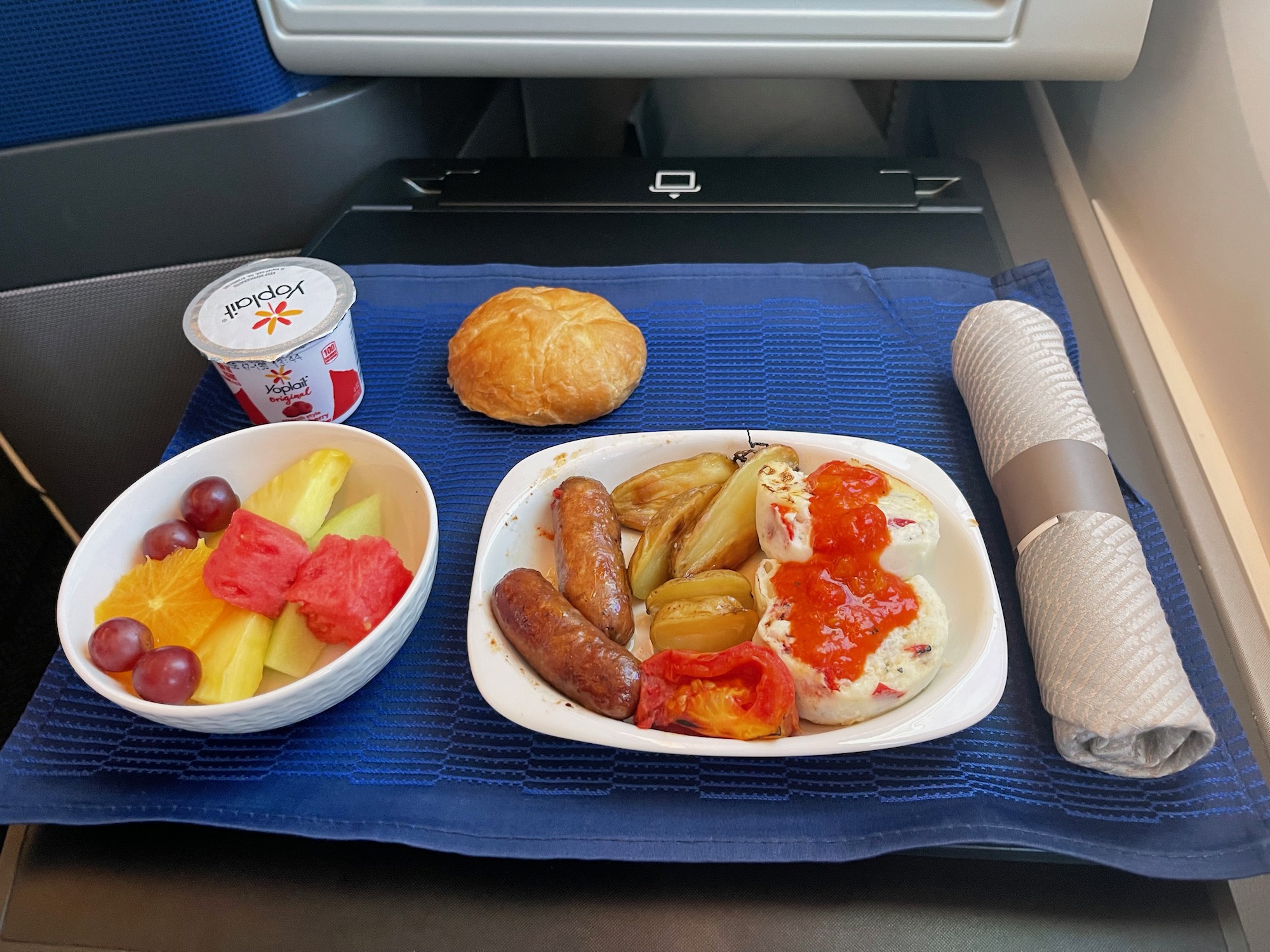 a plate of food and a bowl of fruit on a blue place mat