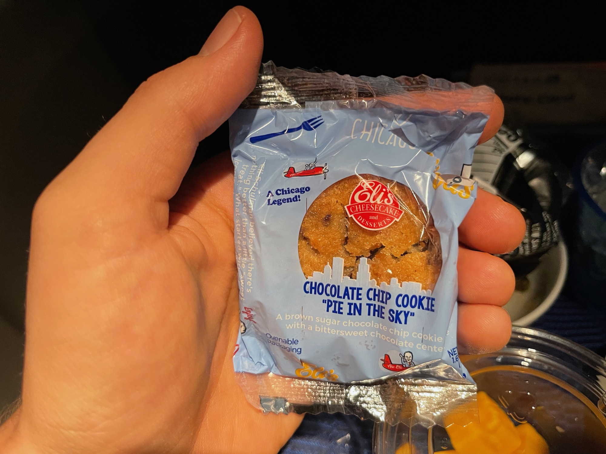 a hand holding a package of chocolate chip cookie