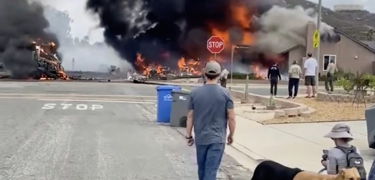 a group of people walking on a road with a building on fire