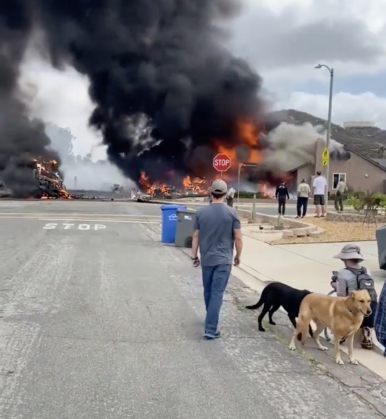 a group of people walking on a road with a building on fire