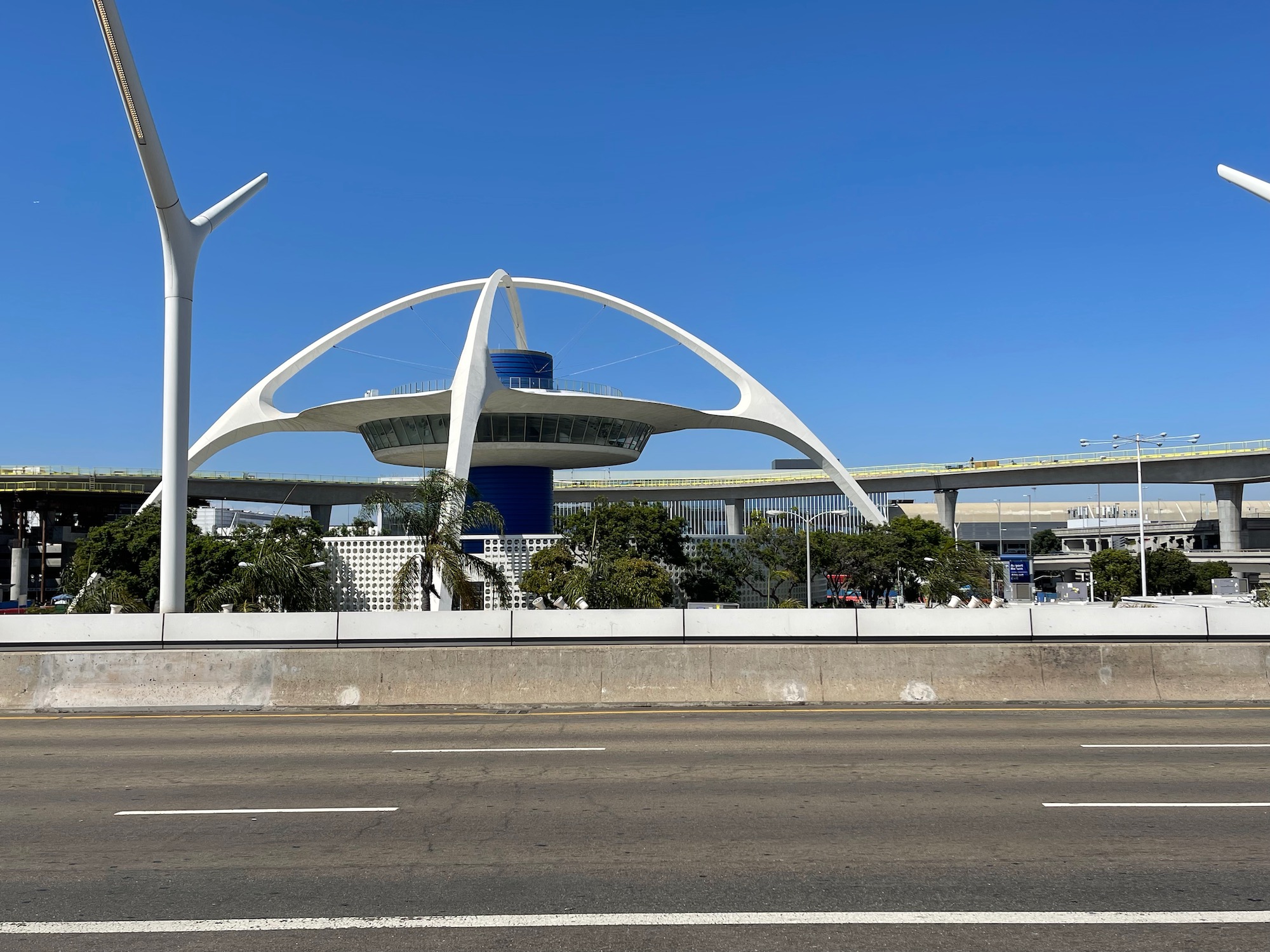 a white structure with a blue roof with Theme Building in the background