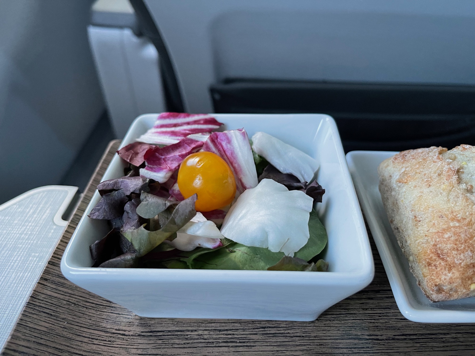 a bowl of salad and a piece of bread