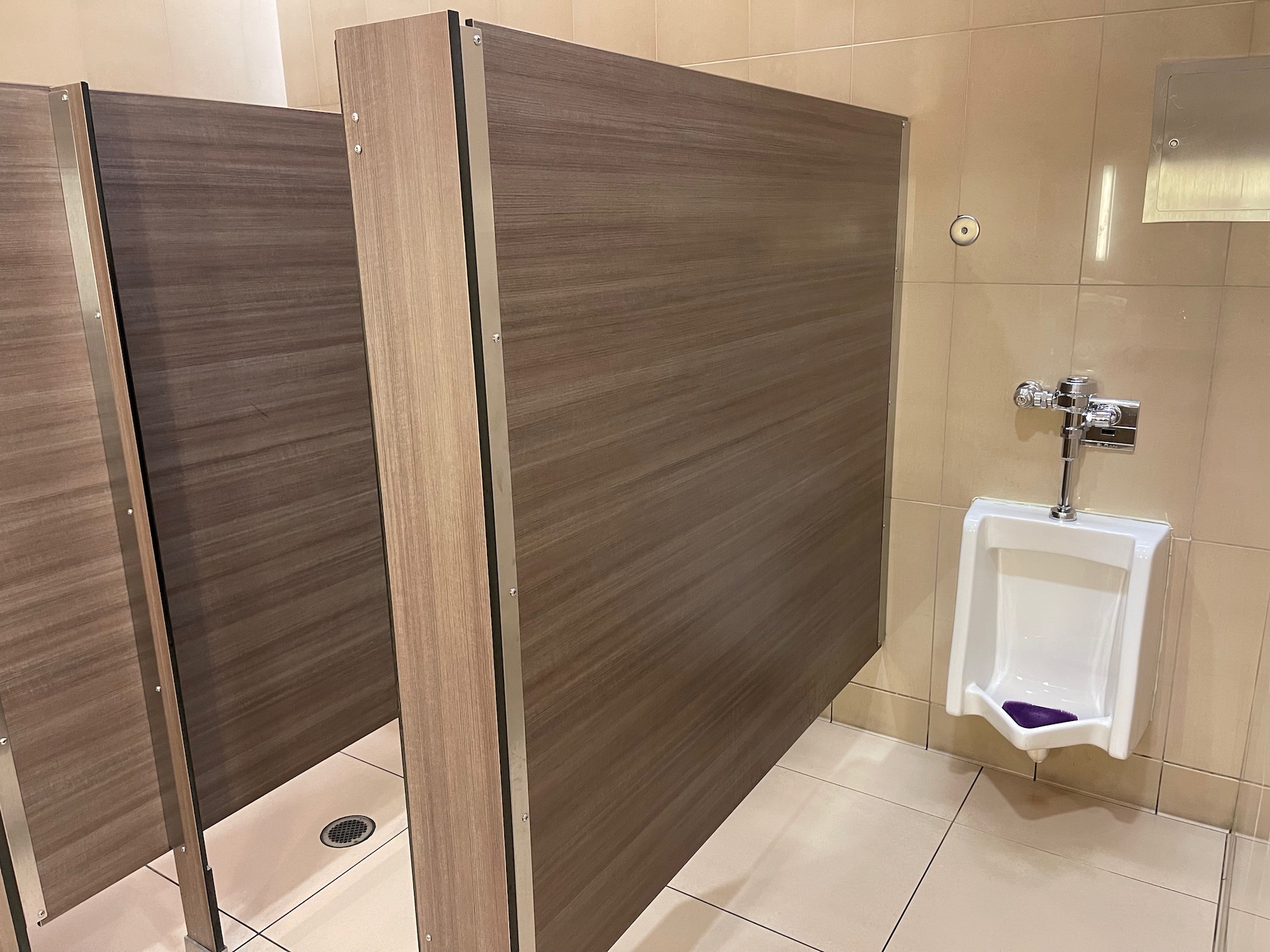 a bathroom with a urinal and a brown partition