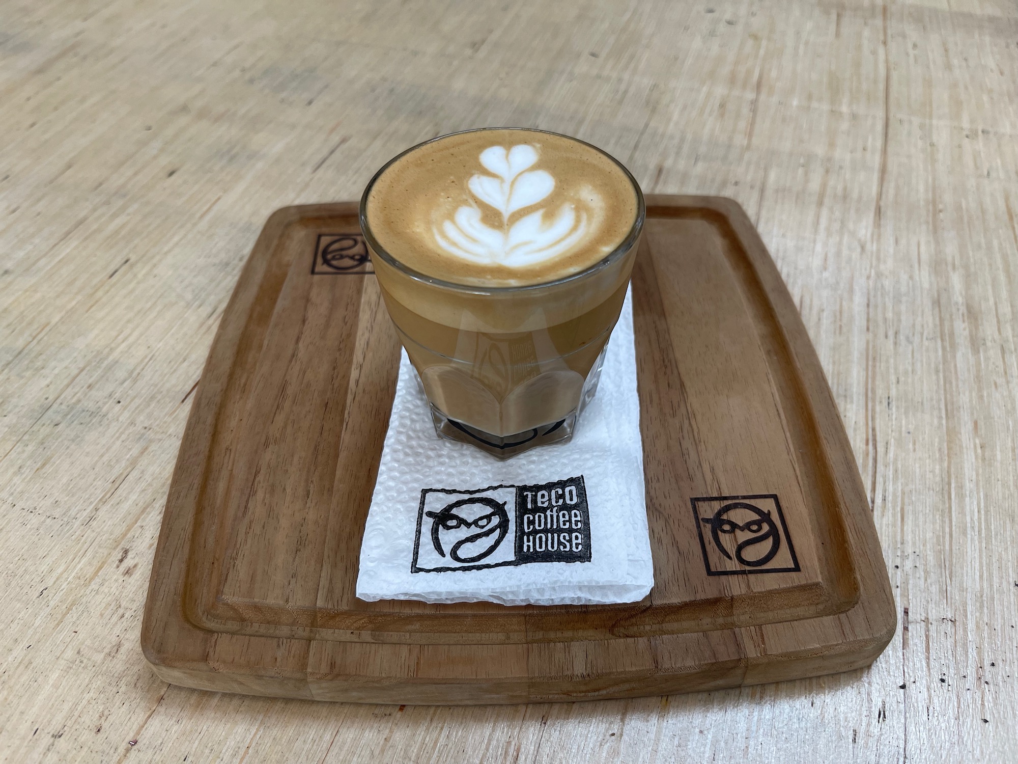 a glass of coffee on a wooden tray