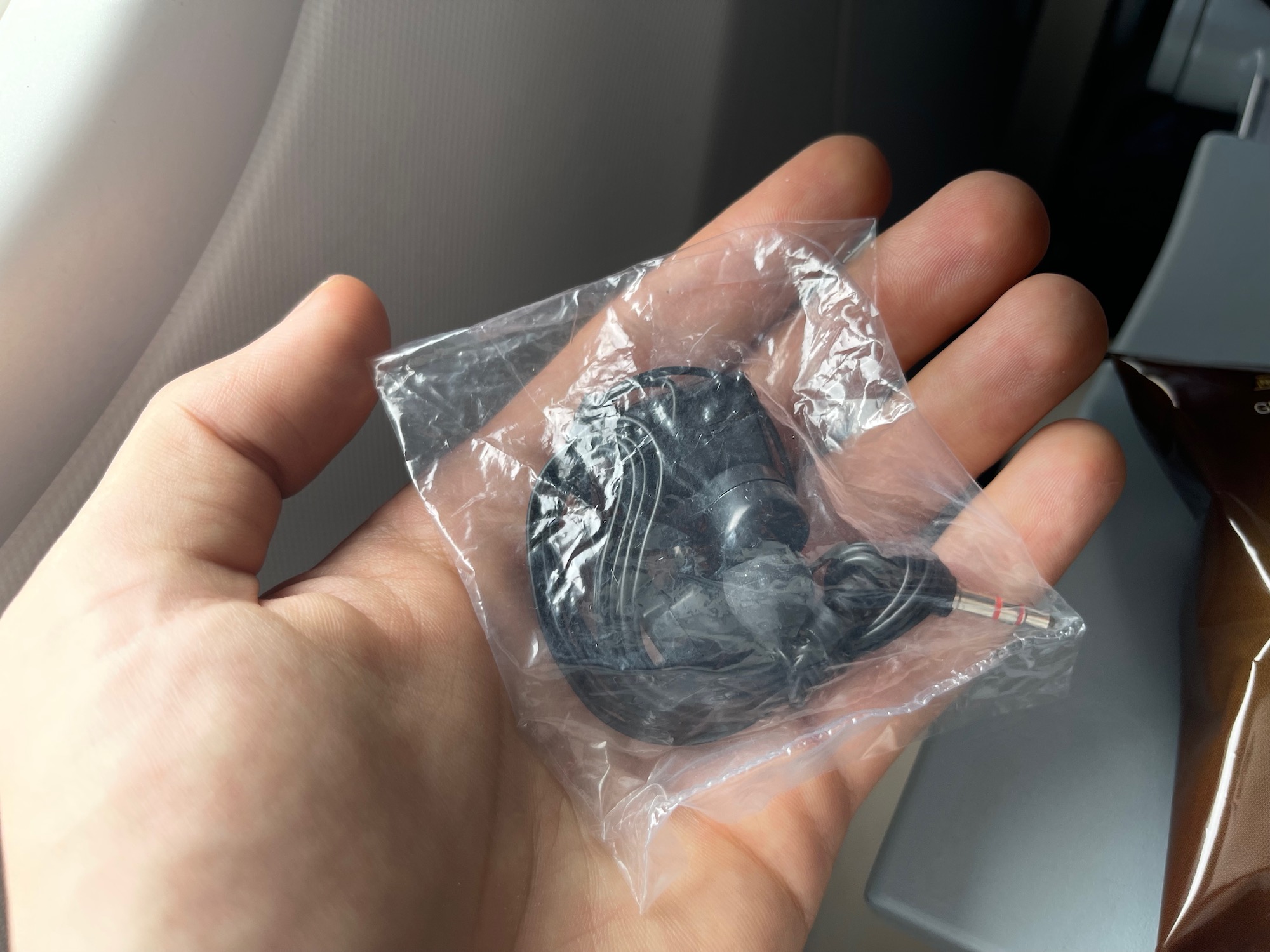 a hand holding a black earbuds in a plastic bag