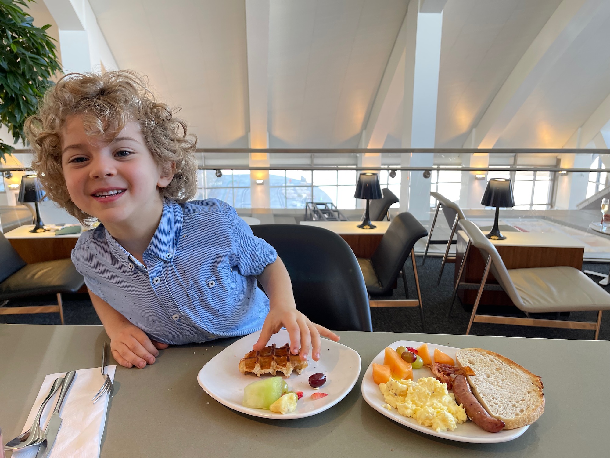 a child sitting at a table with plates of food