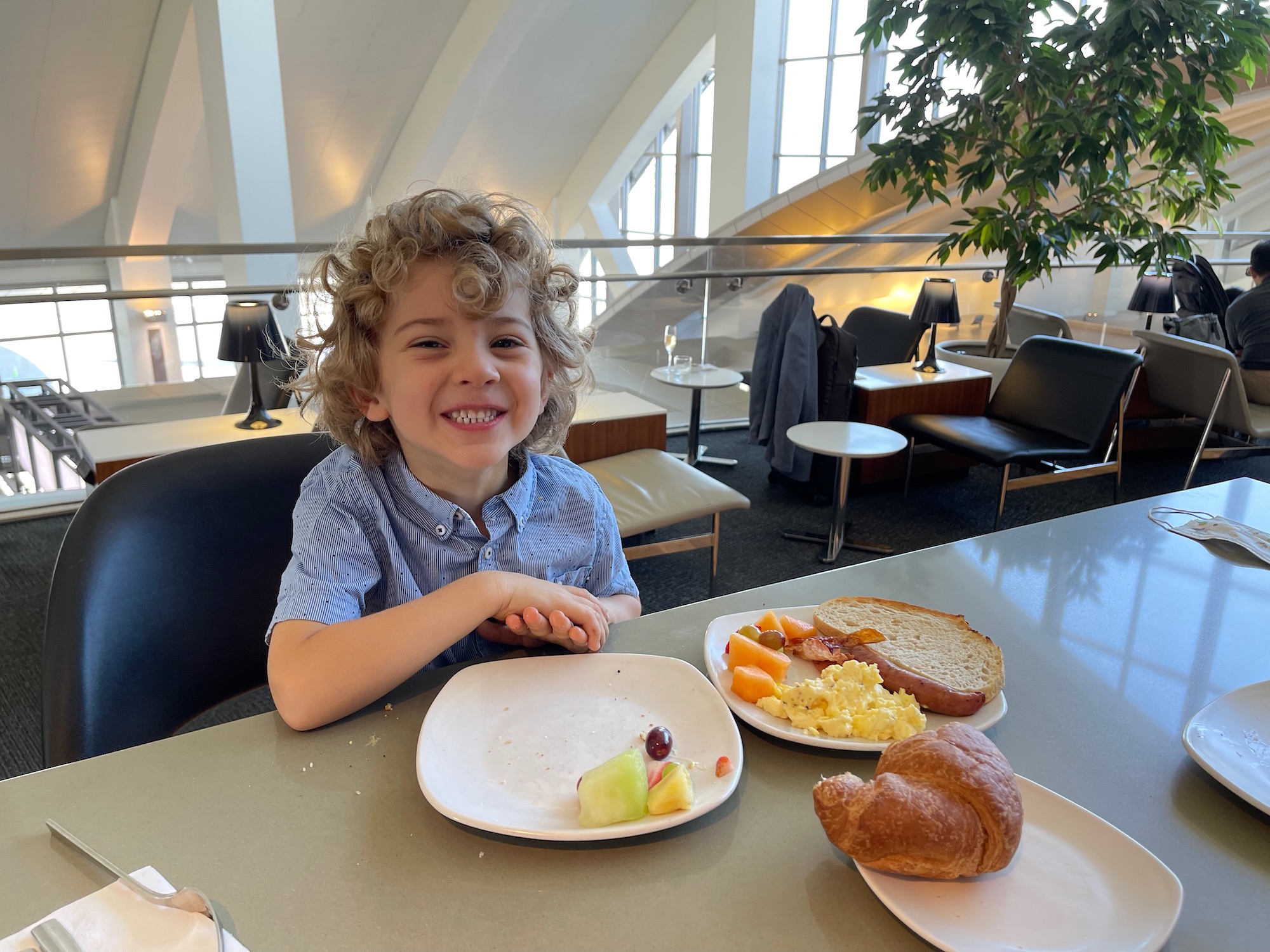 a boy sitting at a table with plates of food