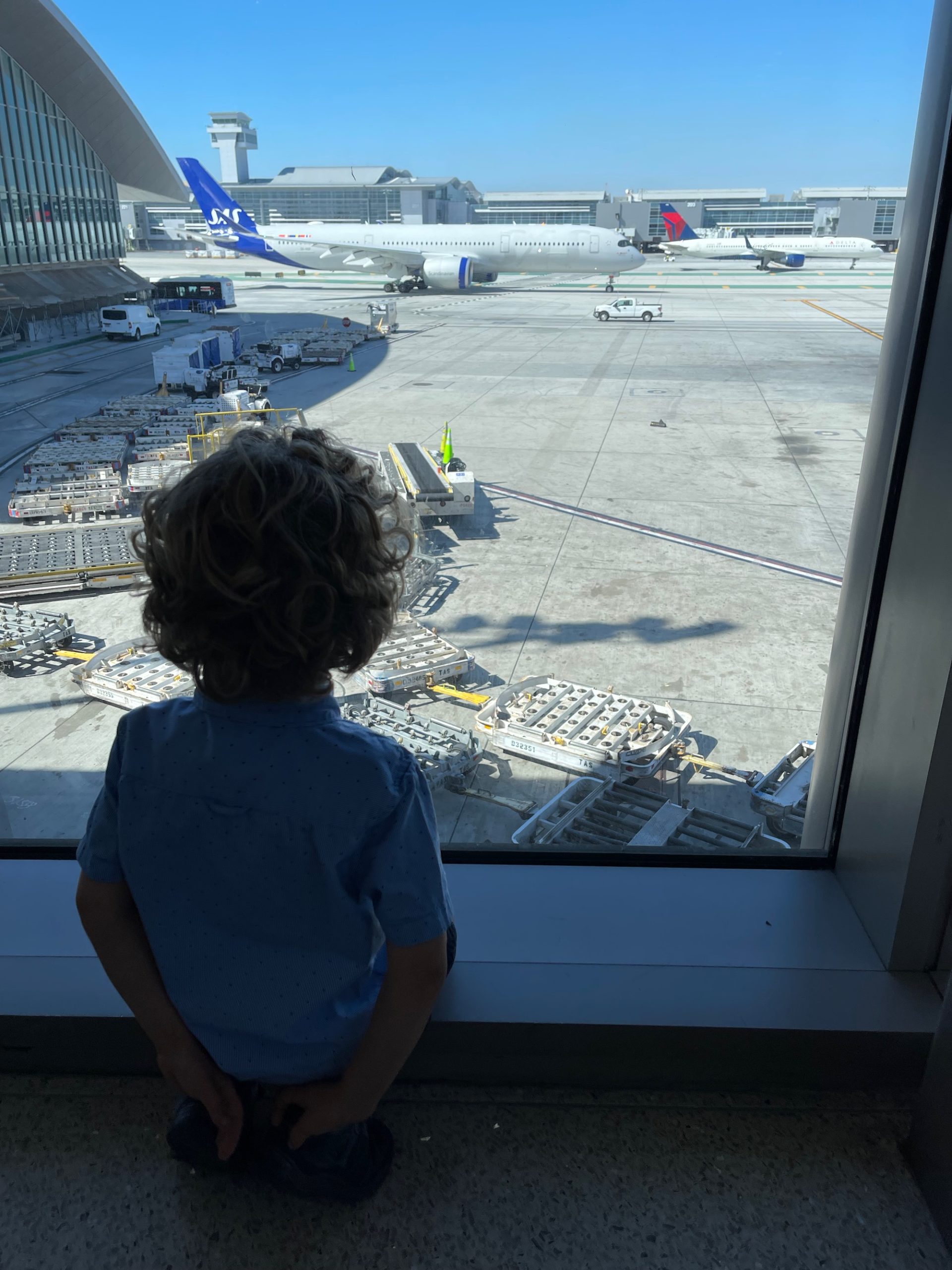 a child looking out a window at an airport