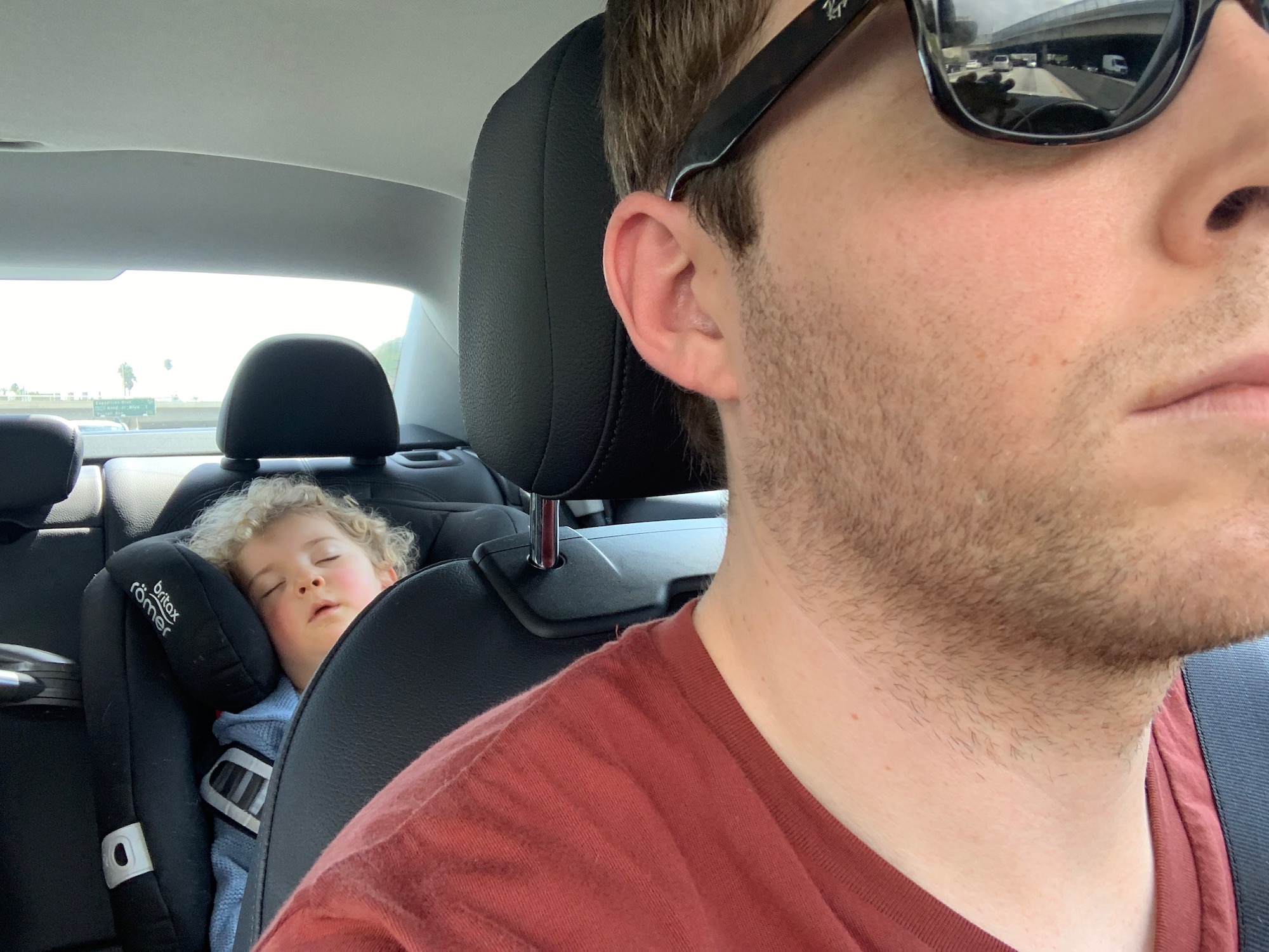 a man in a car with a child sleeping in his lap