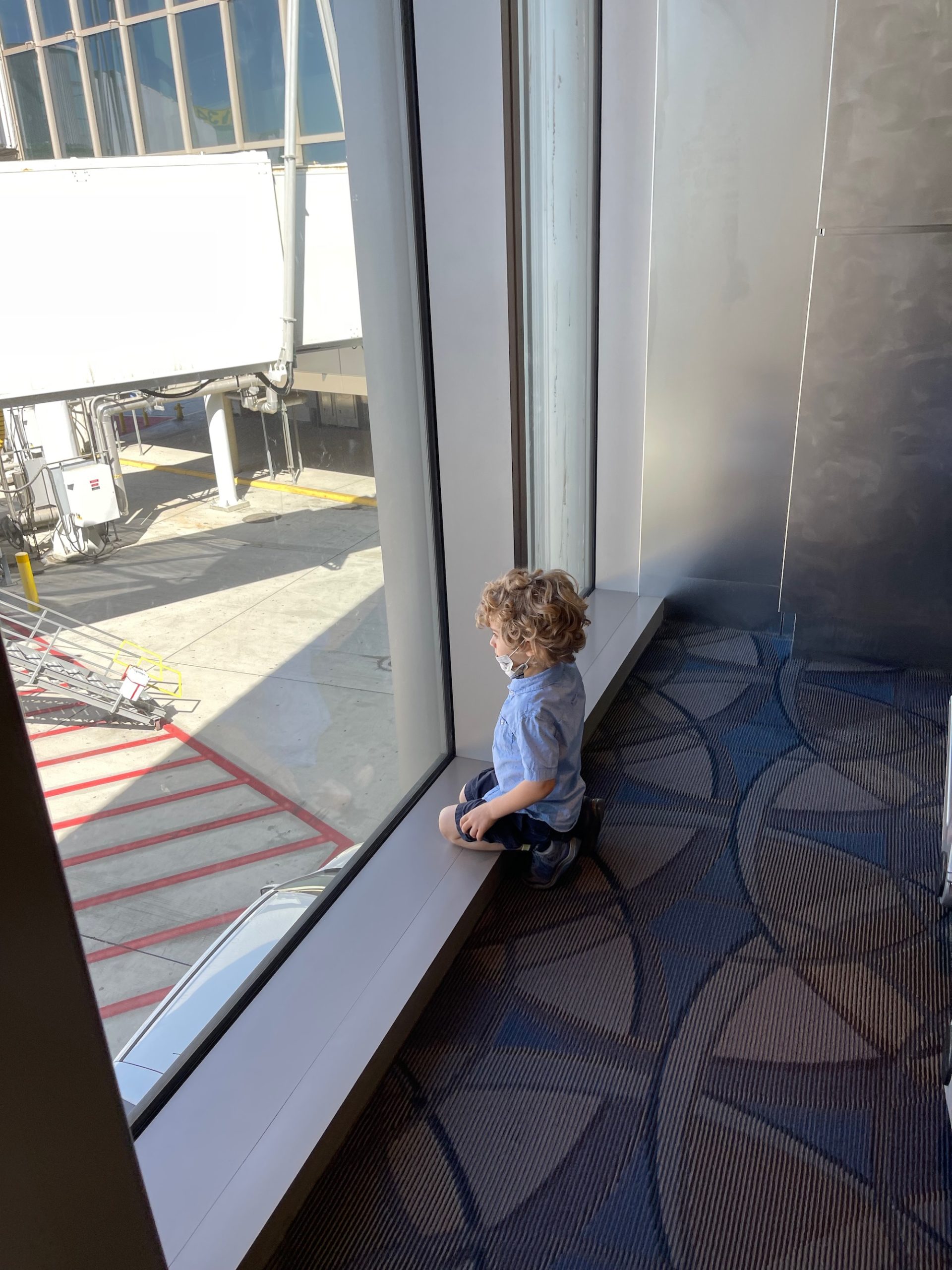 a child sitting on a window sill looking out a window