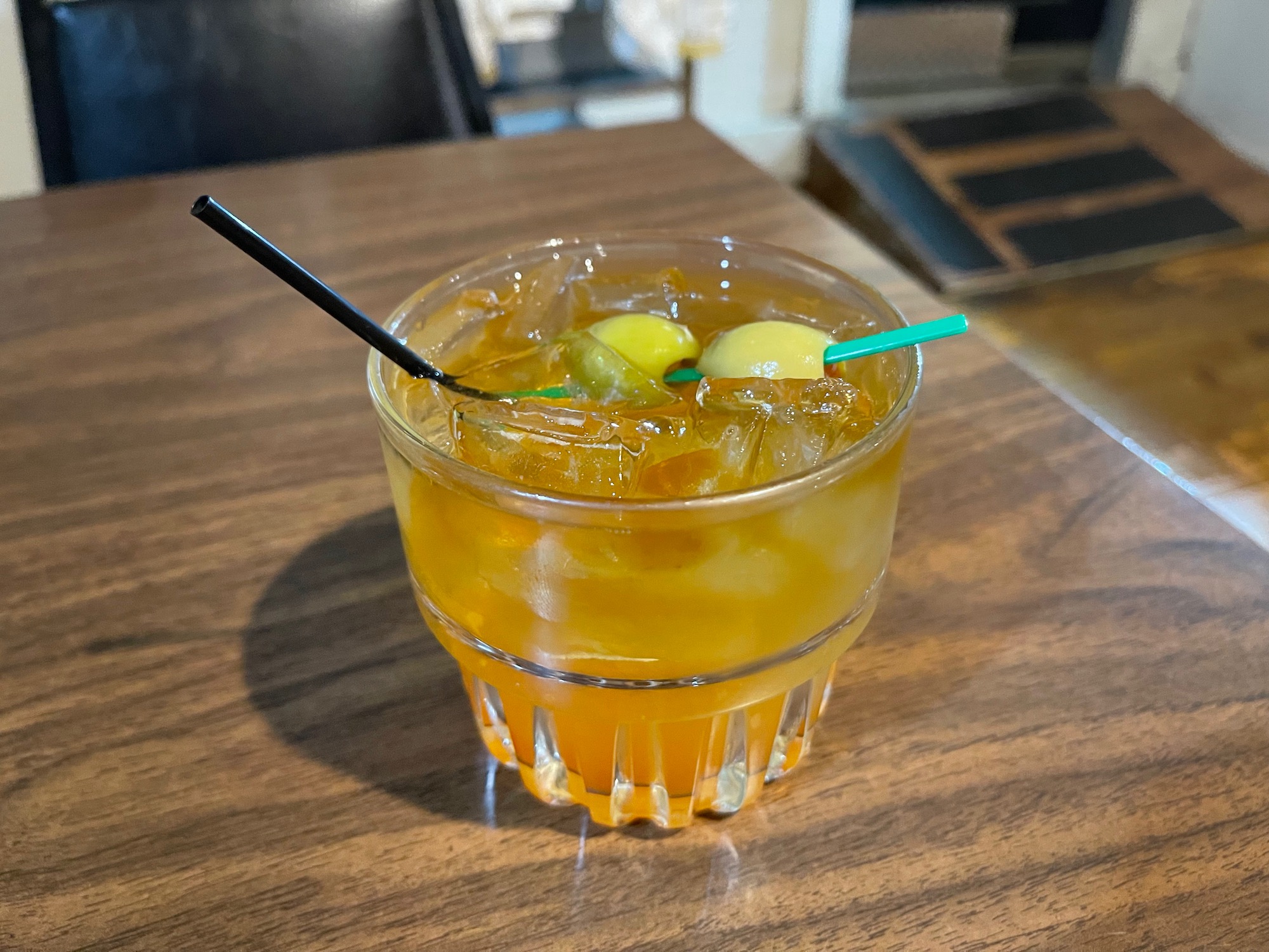 a glass of orange liquid with two straws