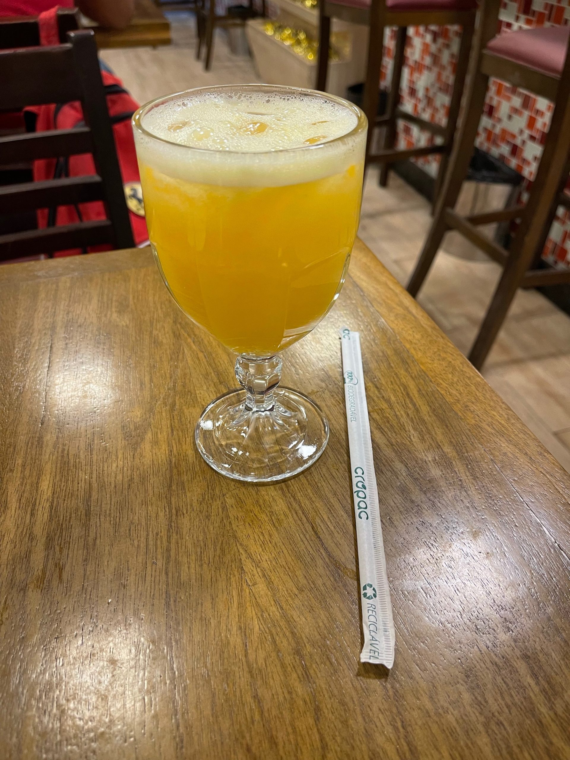 a glass of orange liquid and a straw on a table