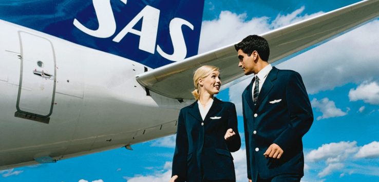 a man and woman in uniform standing next to an airplane