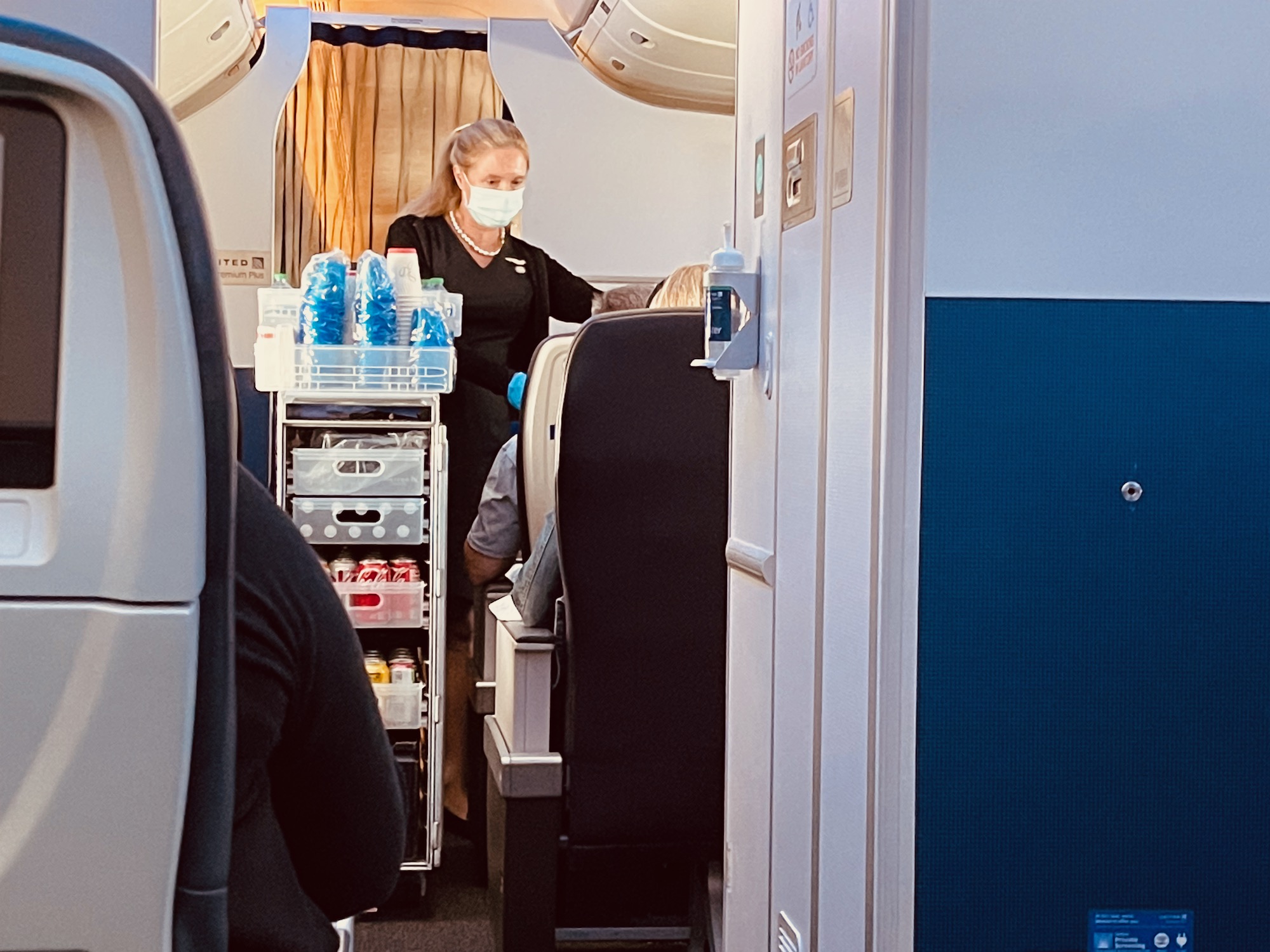 a woman wearing a mask and standing in an airplane