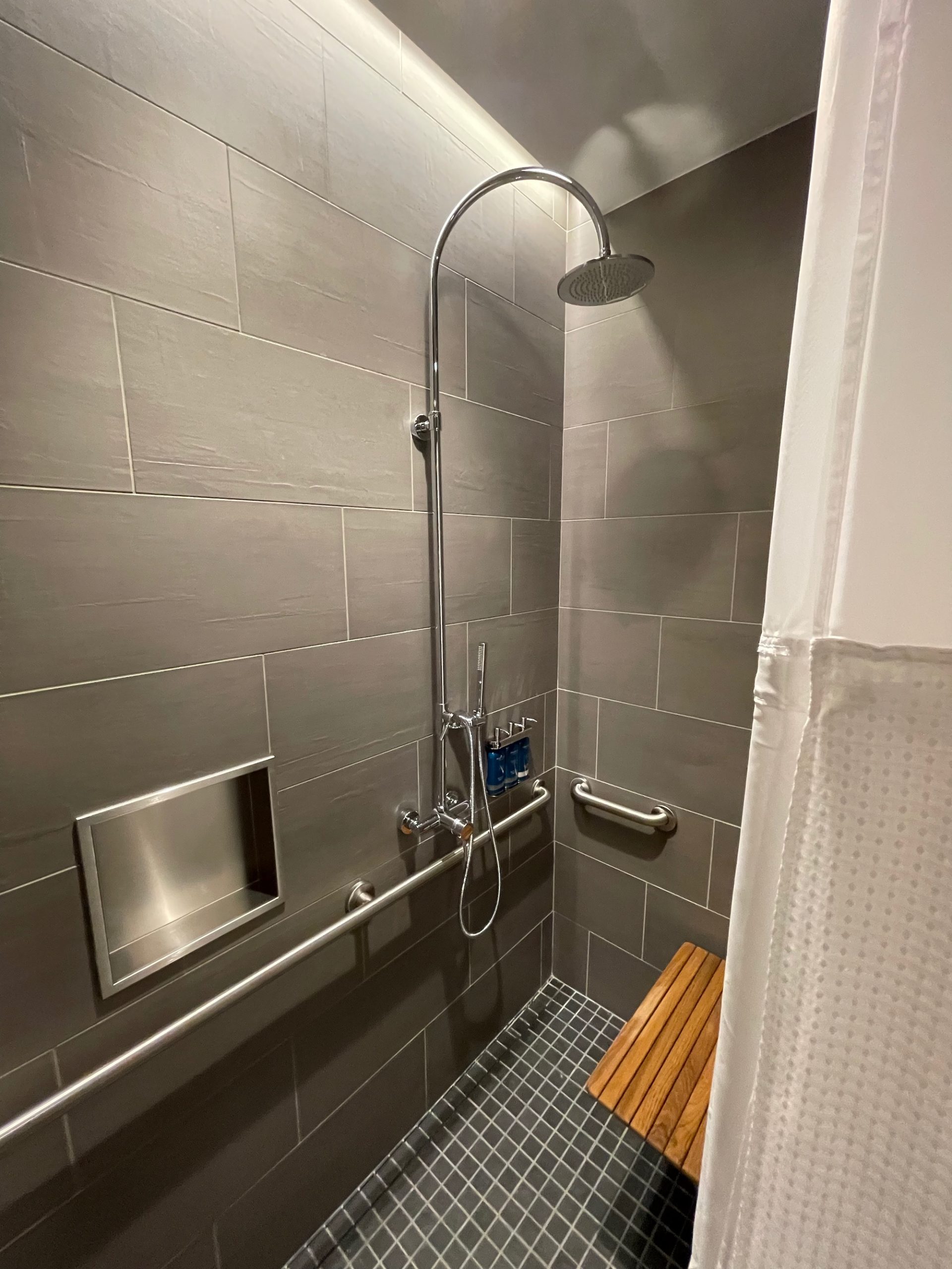 a shower with a bench and a shower head