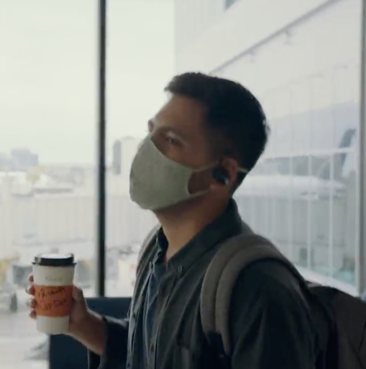 a man wearing a mask and holding a coffee cup