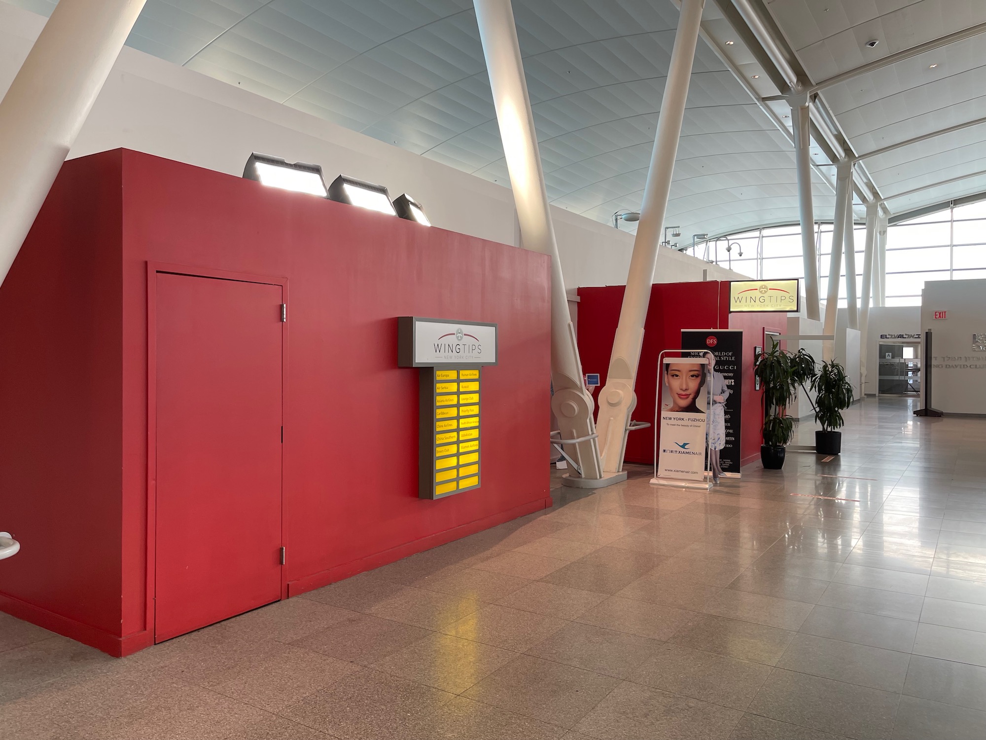 a red wall with a sign and a plant