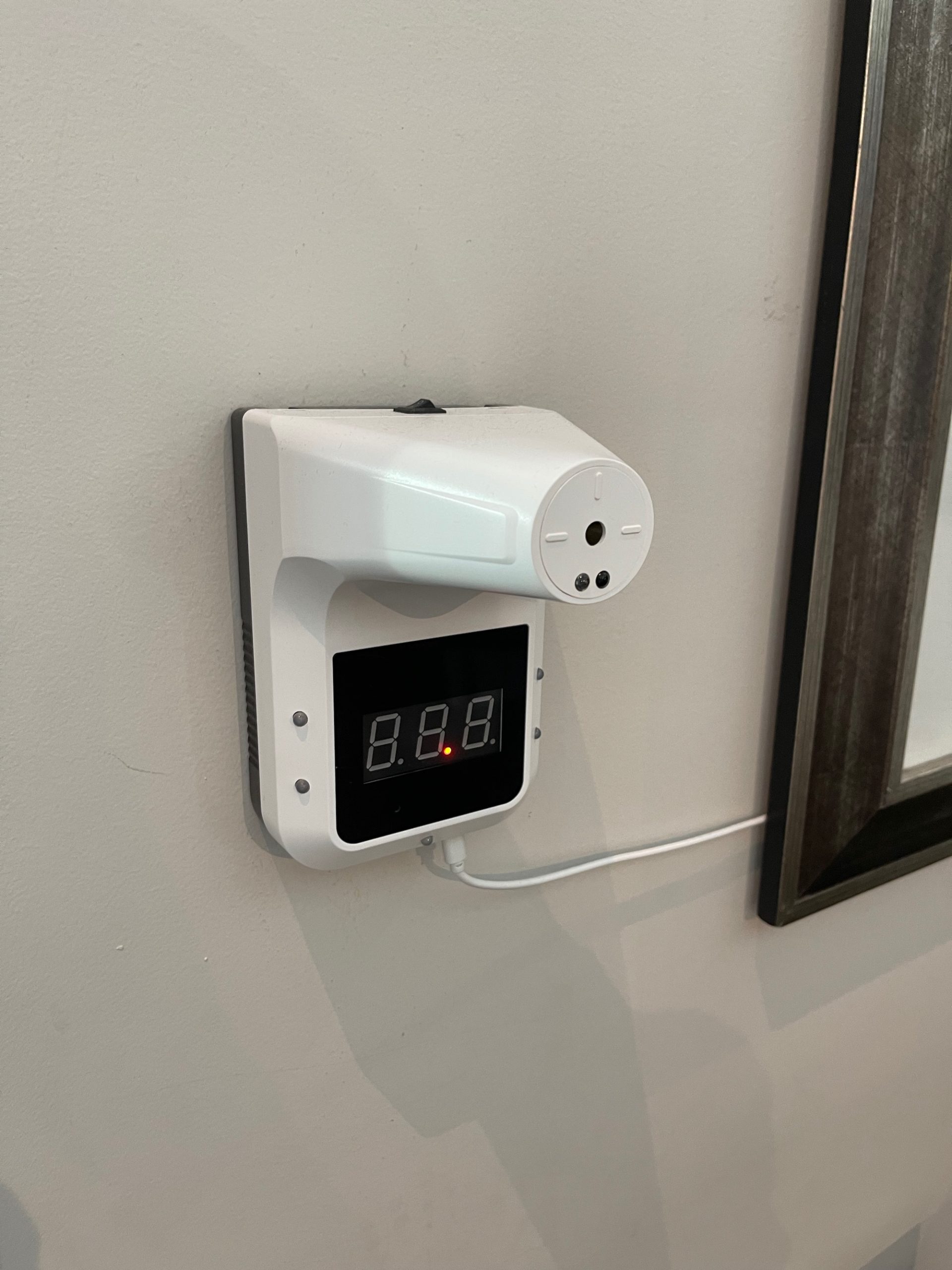 a white device with a digital display on a wall