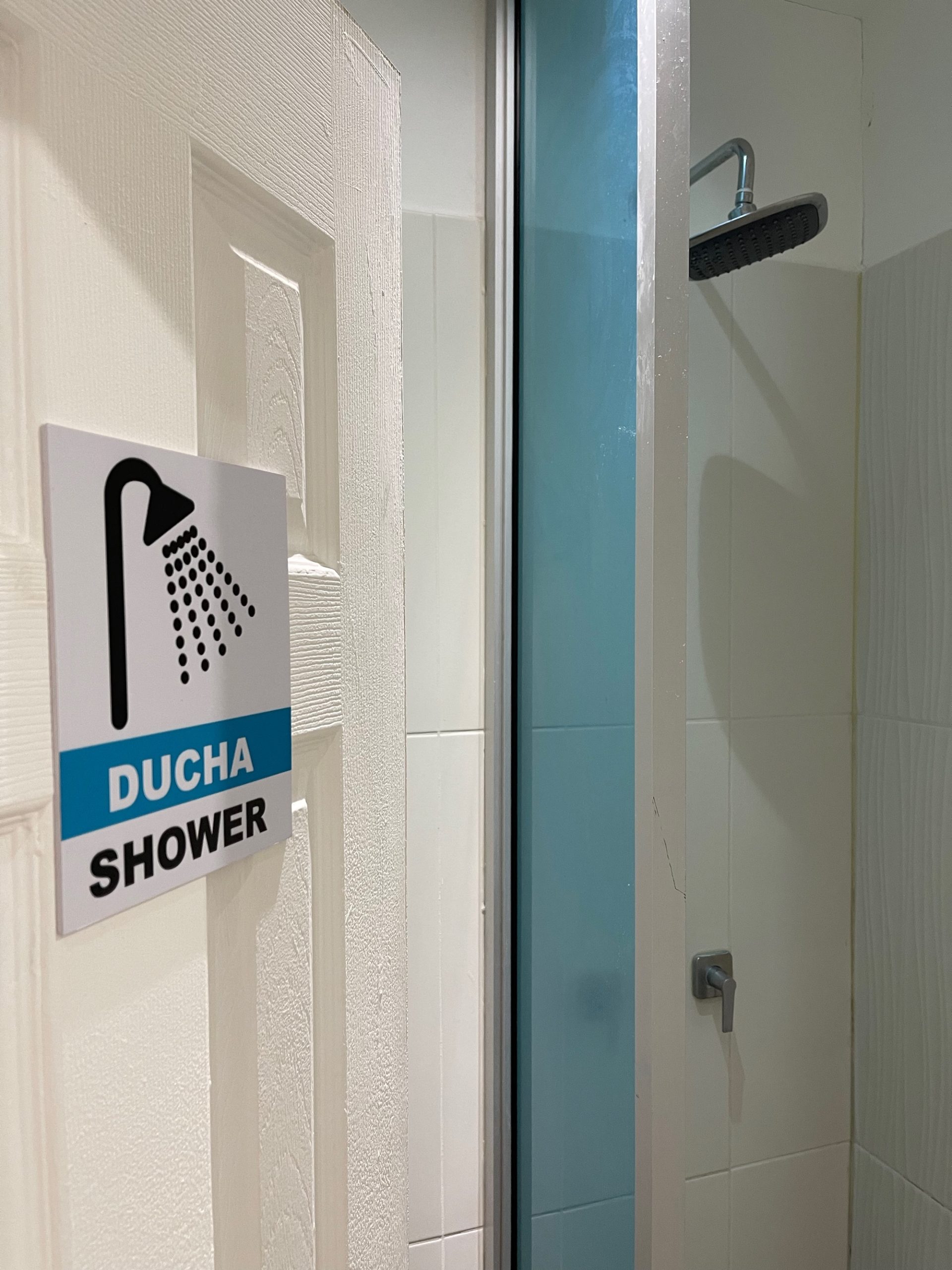 a shower with a sign on the wall