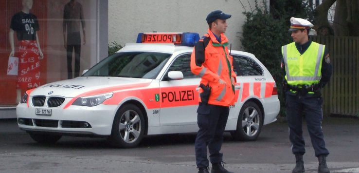 two police officers standing in front of a white car