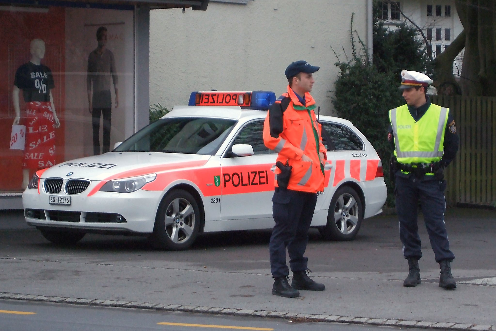 two police officers standing in front of a white car