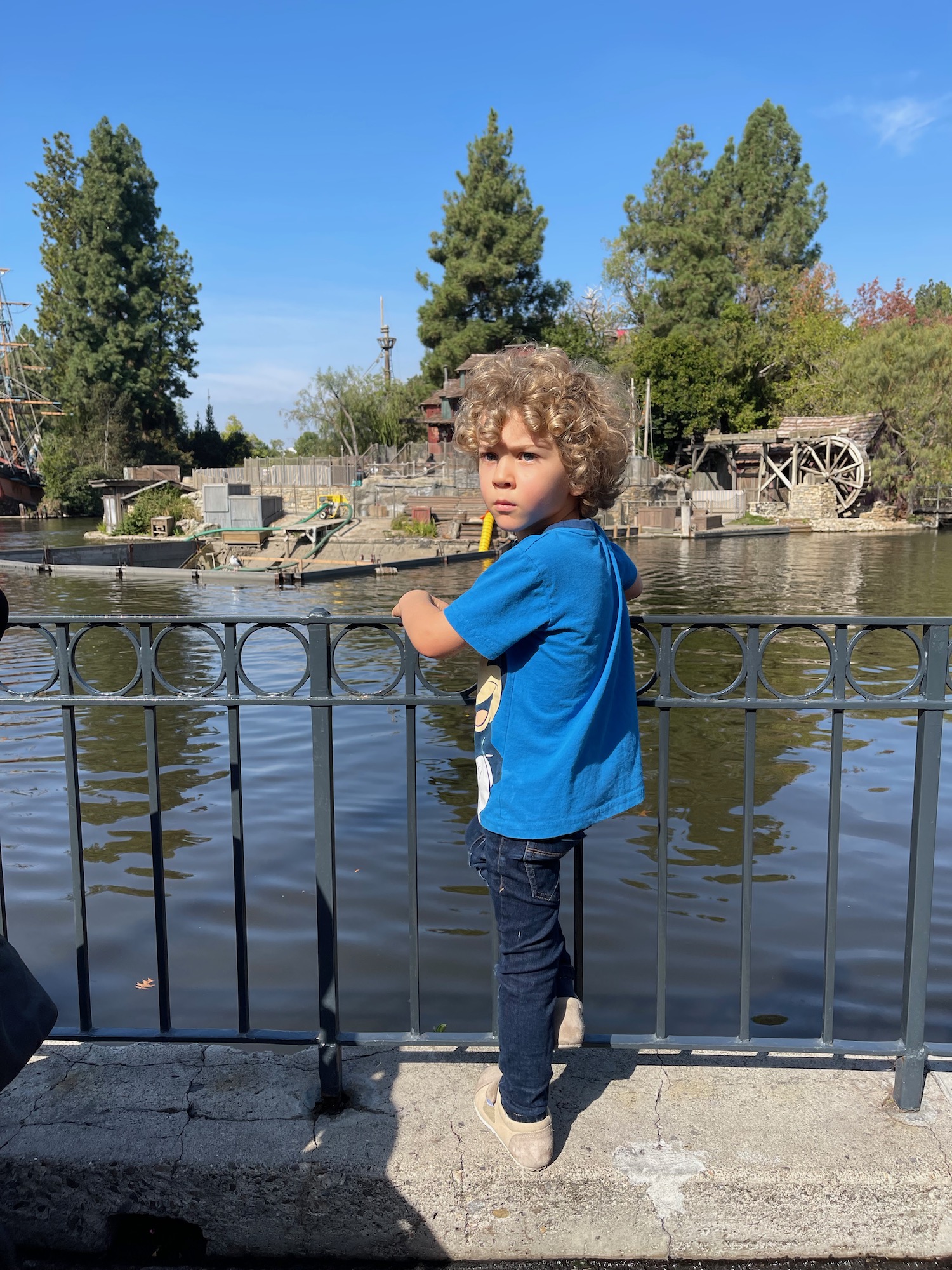 a boy standing on a bridge by water