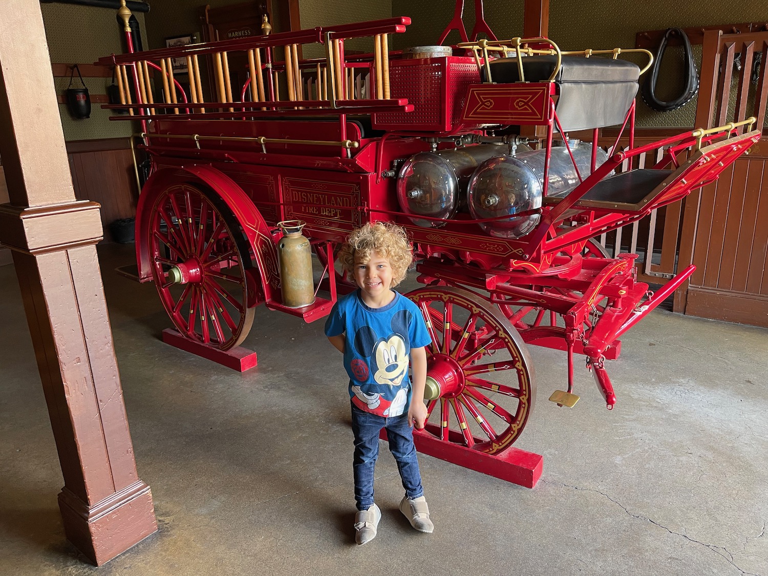 a boy standing in front of a red fire engine