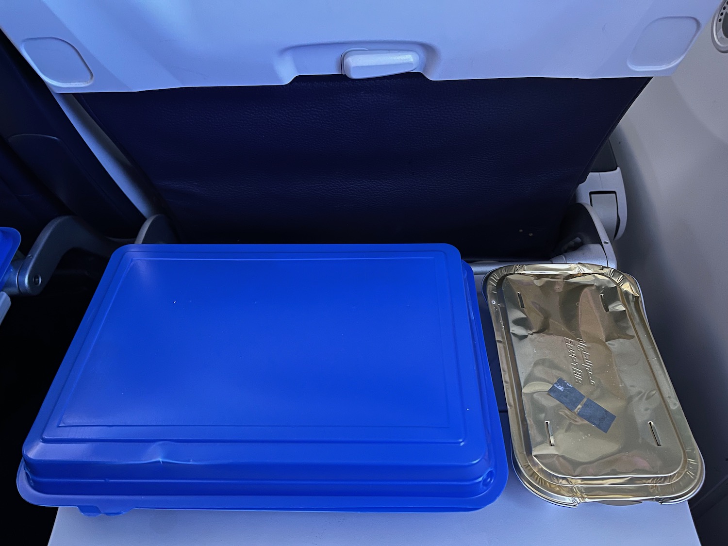 a blue food container in the back of a plane