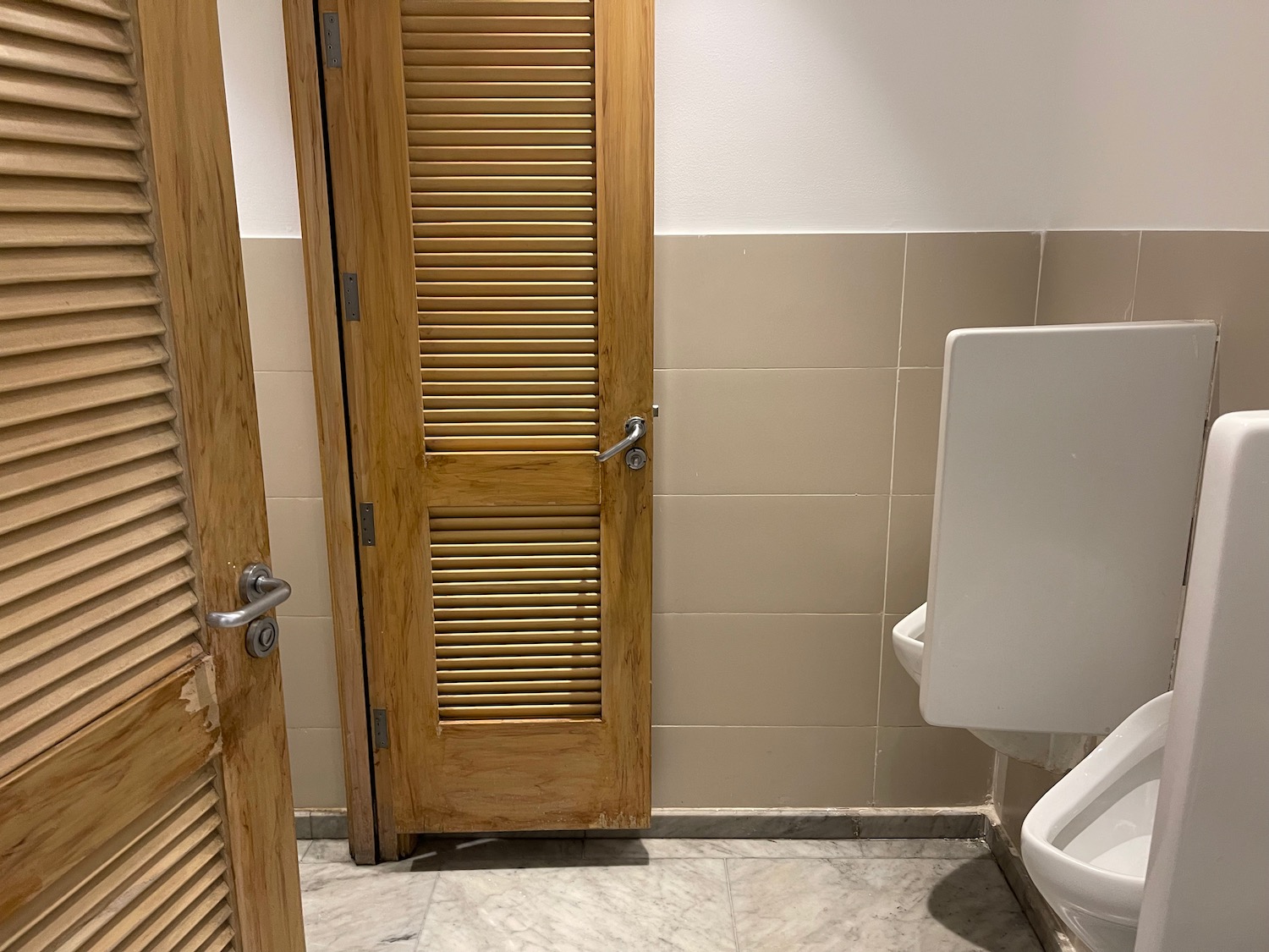 a wooden door next to a urinal