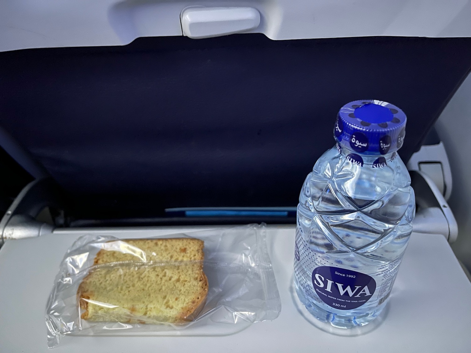 a bottle of water and a piece of bread on a tray