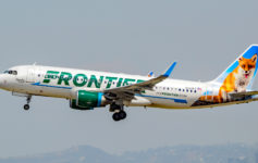 a white airplane with green and blue text flying in the sky