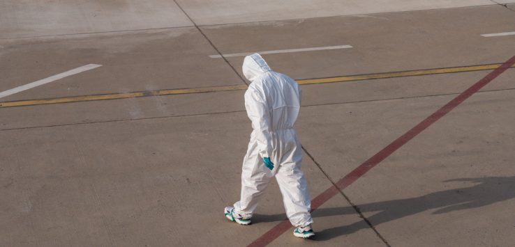 a person in a white suit walking on a concrete surface