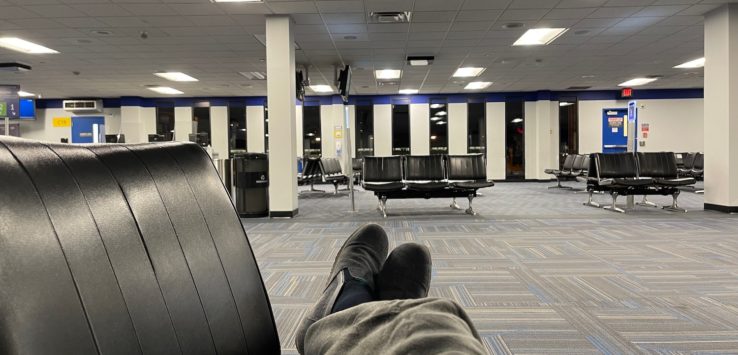 a person's legs in a chair in an airport terminal