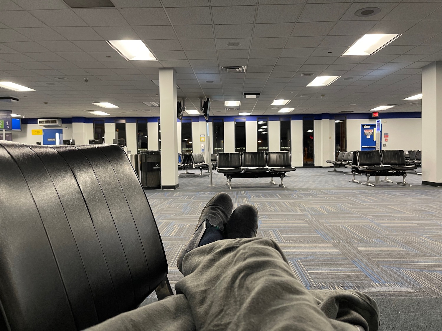 a person's legs in a chair in an airport terminal