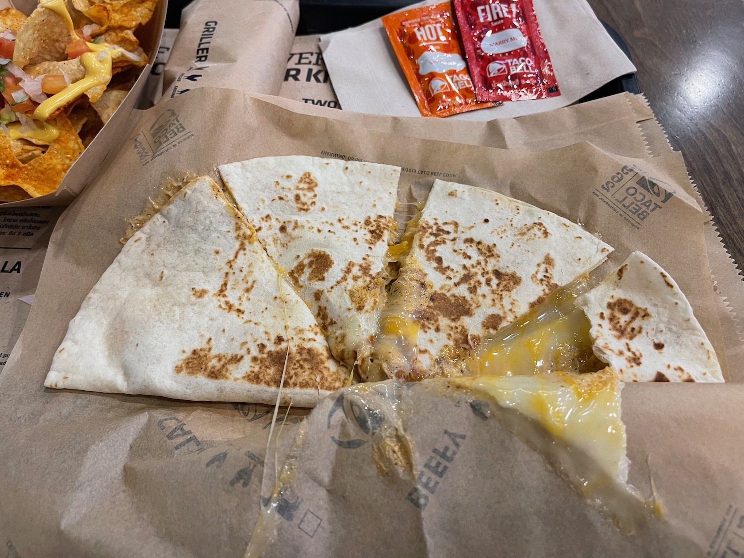 quesadilla on a paper bag with a couple of packets of condiments