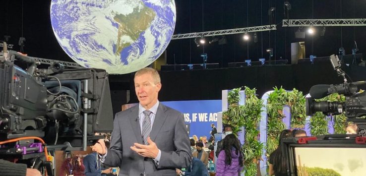 a man in a suit standing in front of a large globe