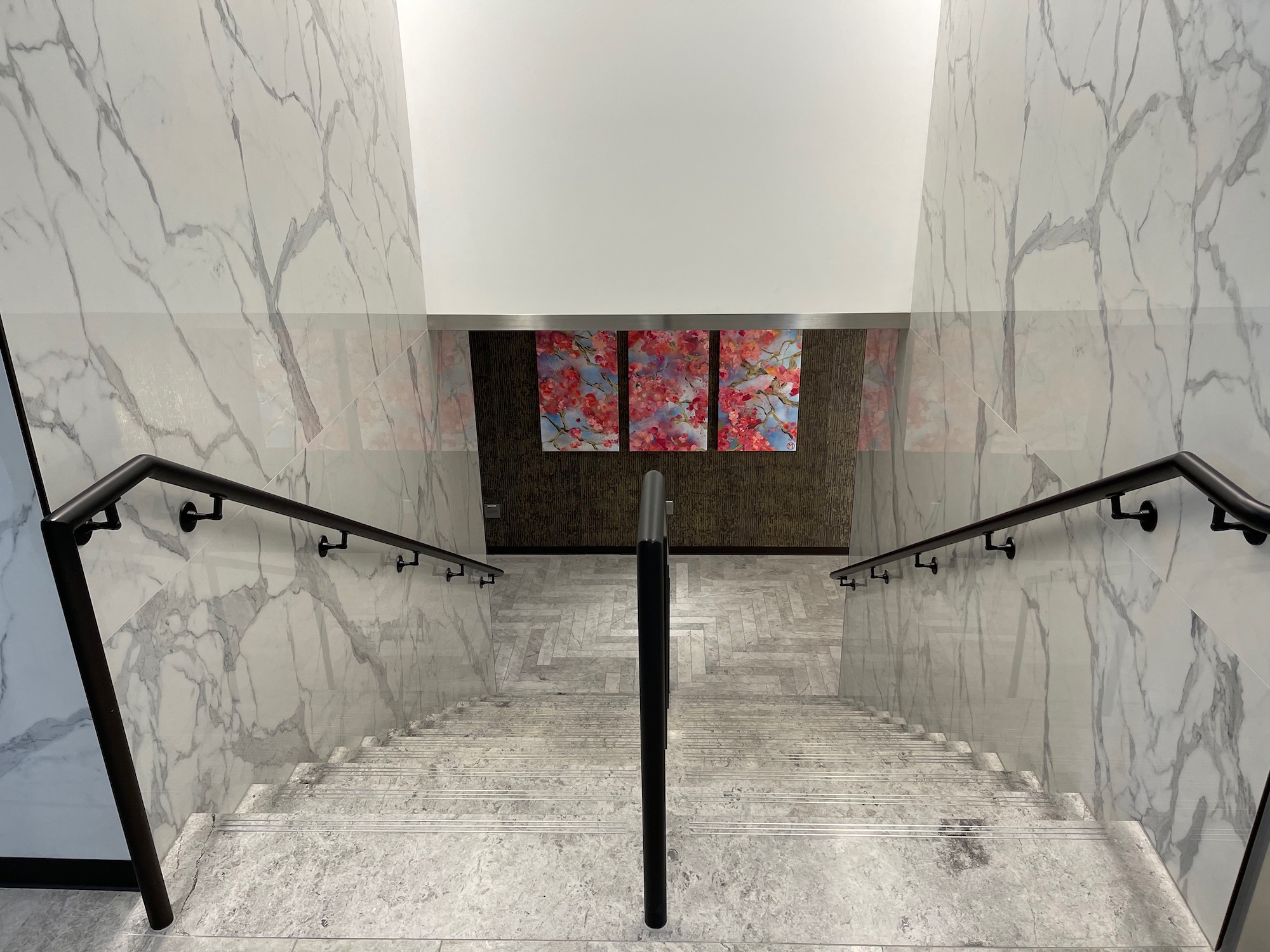 a staircase with marble walls and black handrails