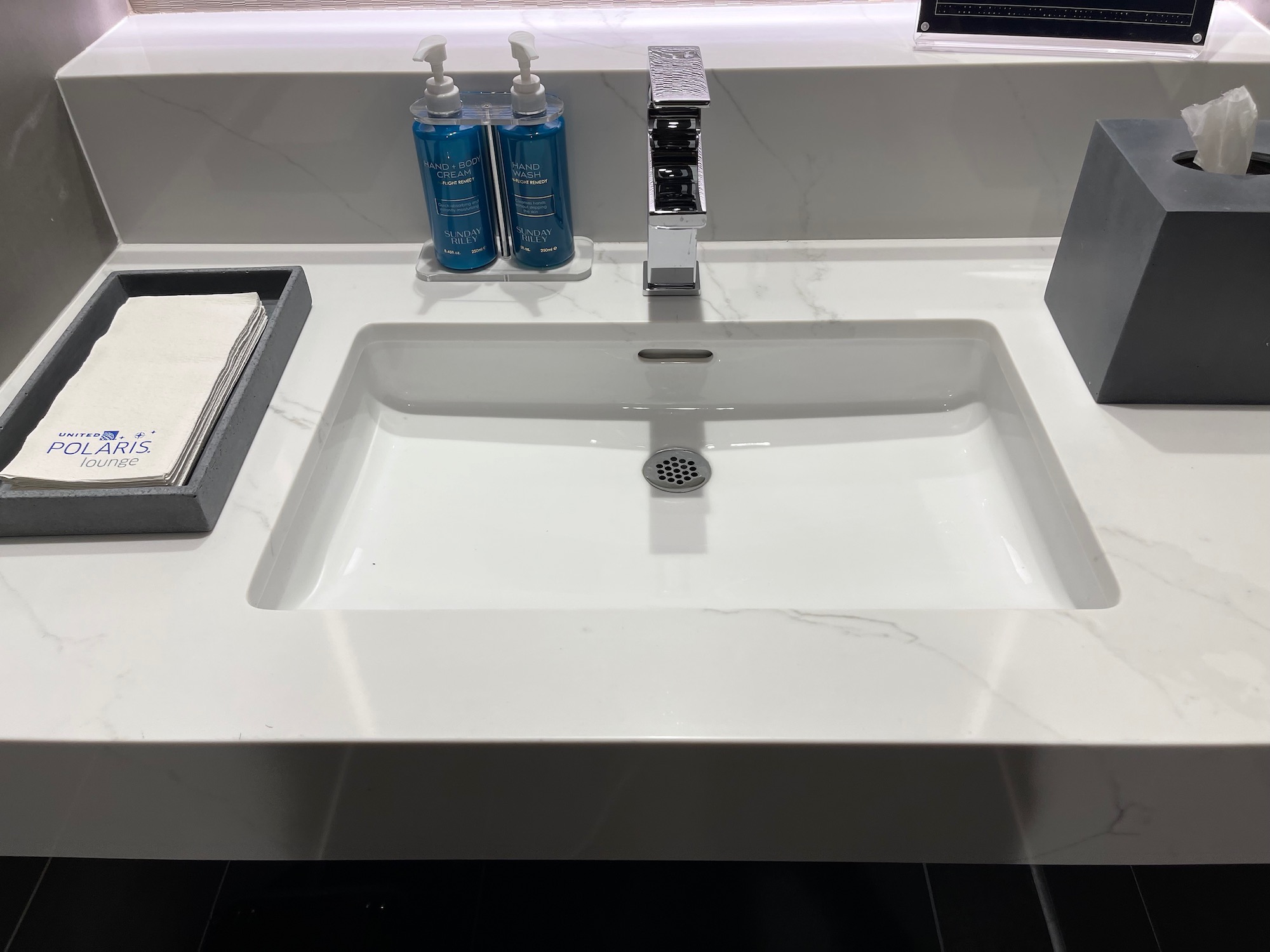 a white sink with two bottles of liquid on it