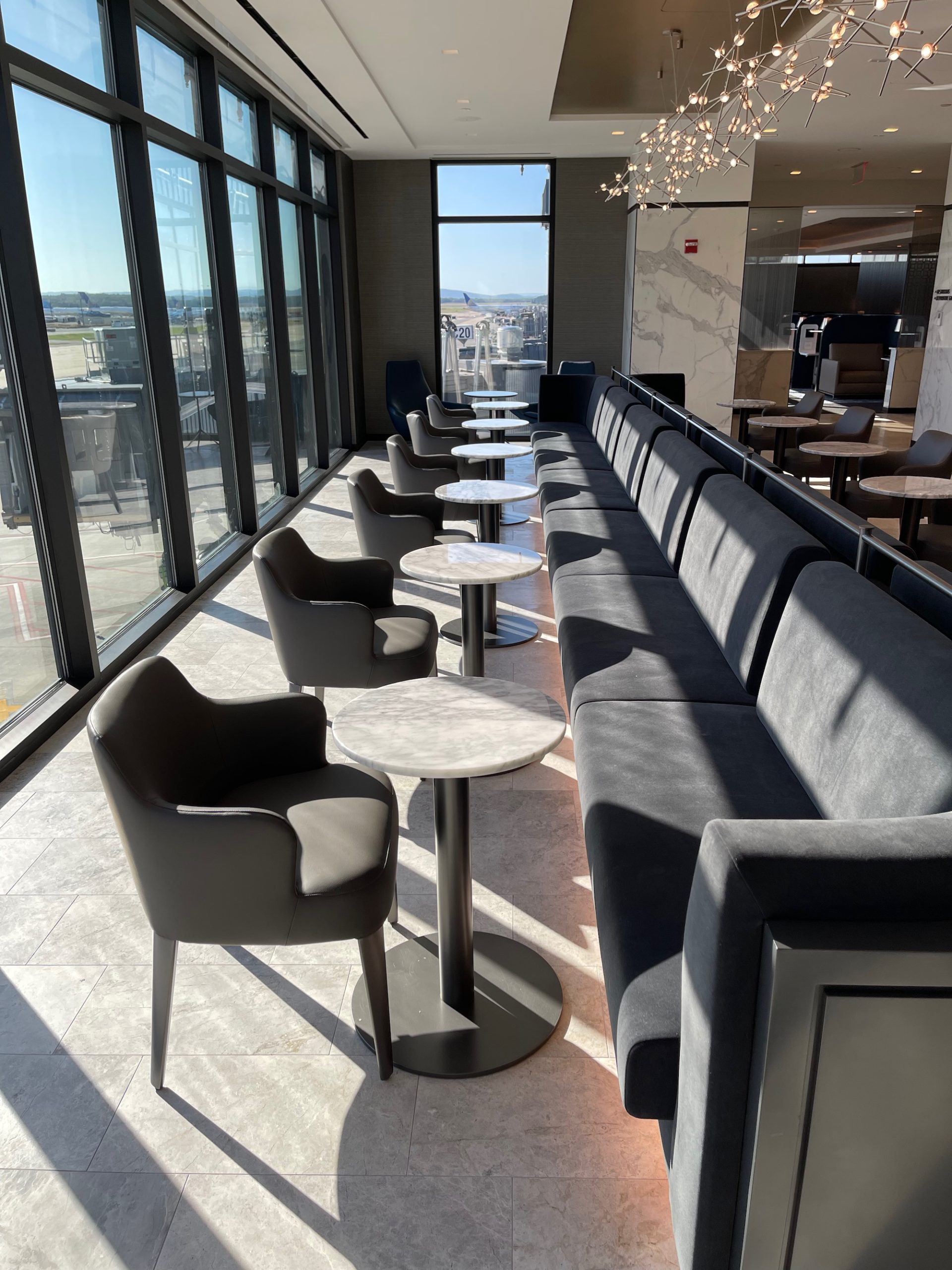 a row of chairs and tables in a room with windows