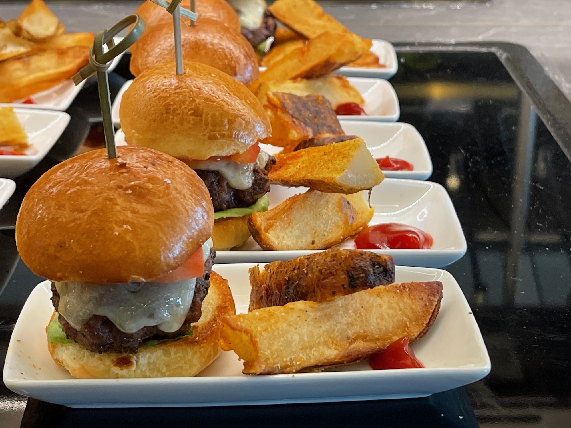 a row of small burgers on white plates