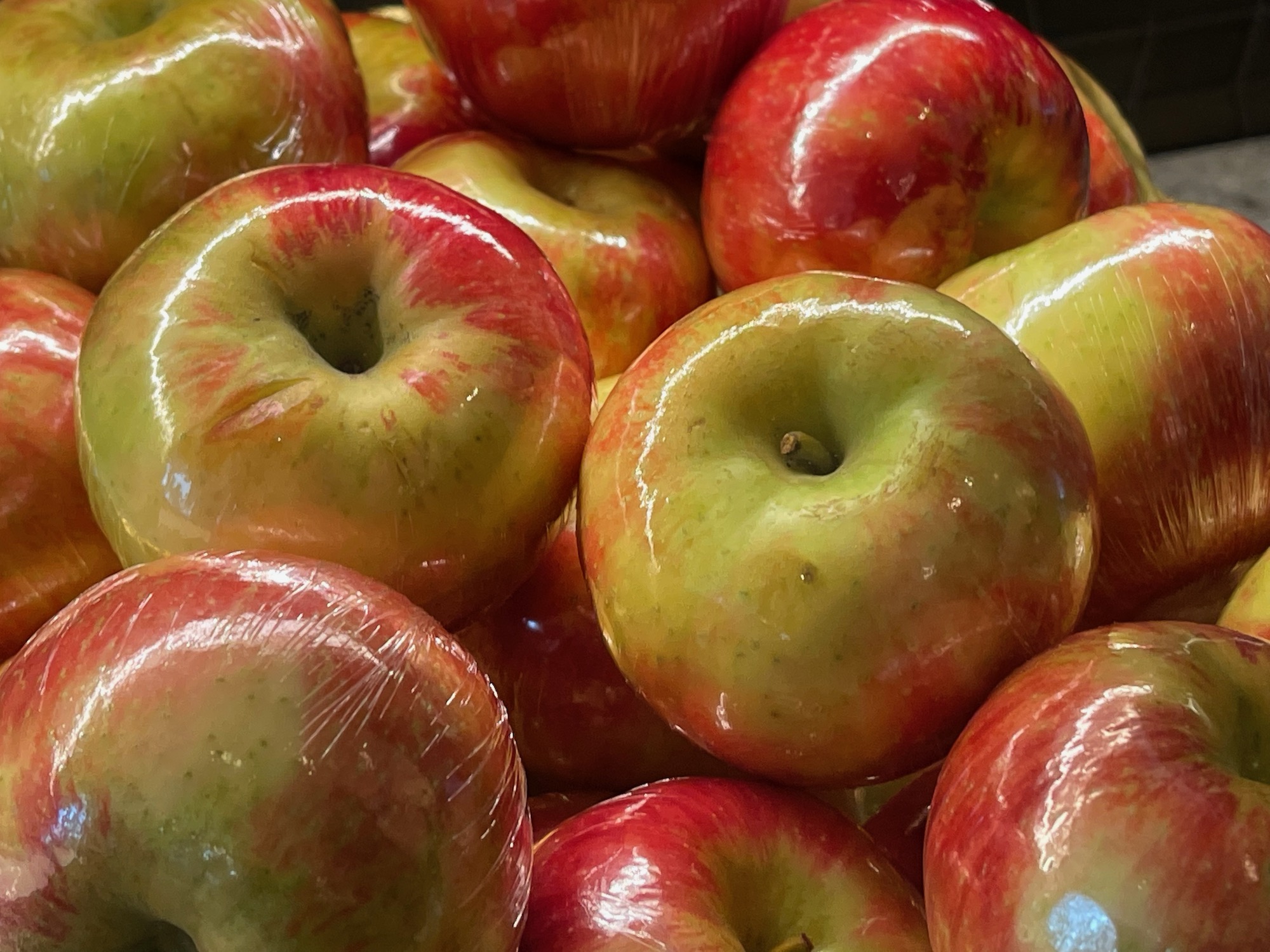 a pile of apples in plastic wrap