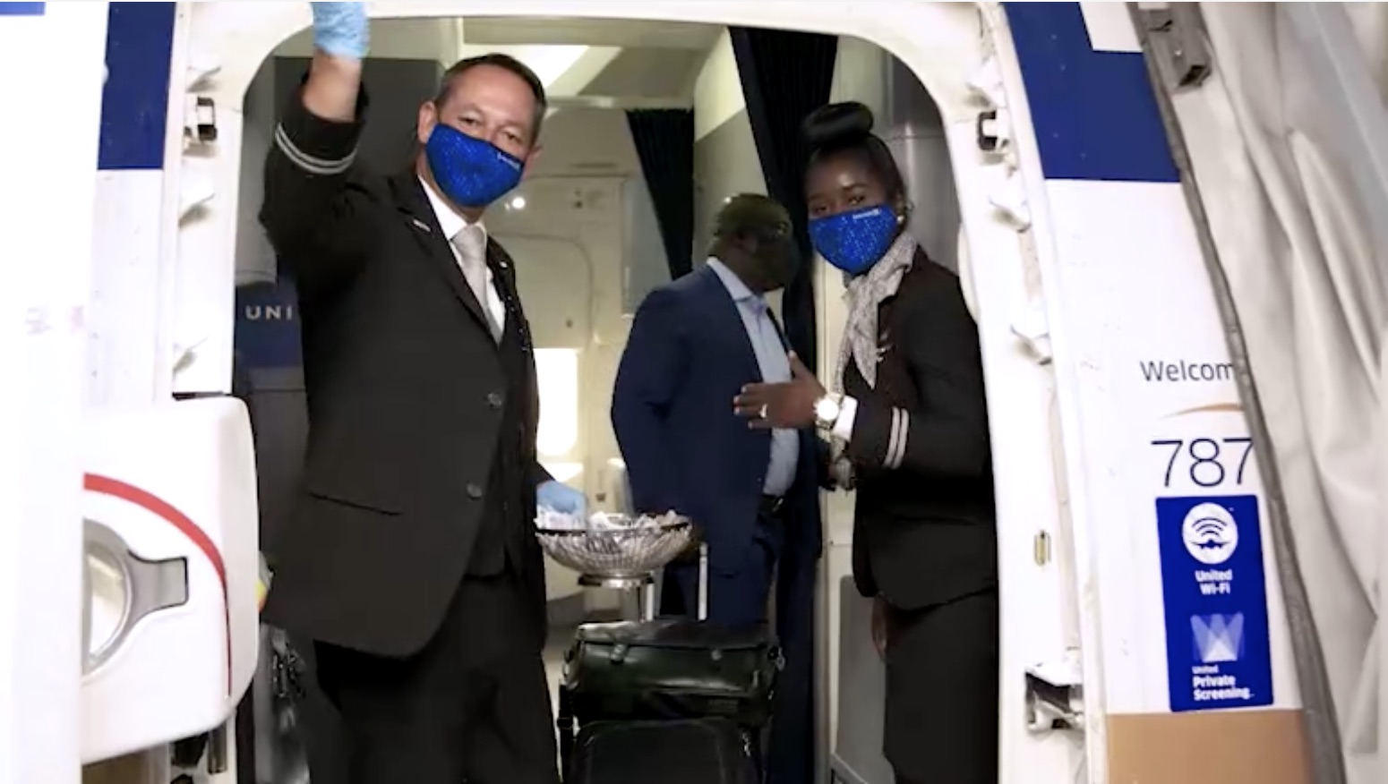 a man and woman wearing face masks and standing in an airplane