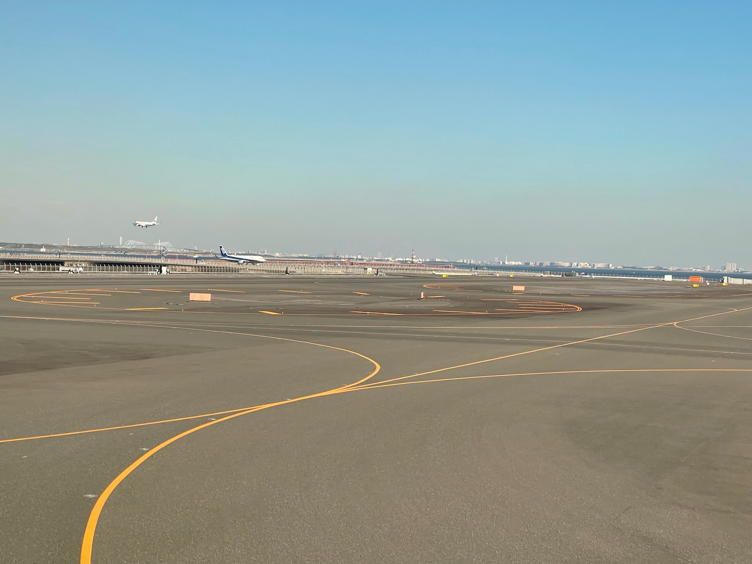 an airport runway with an airplane flying in the sky